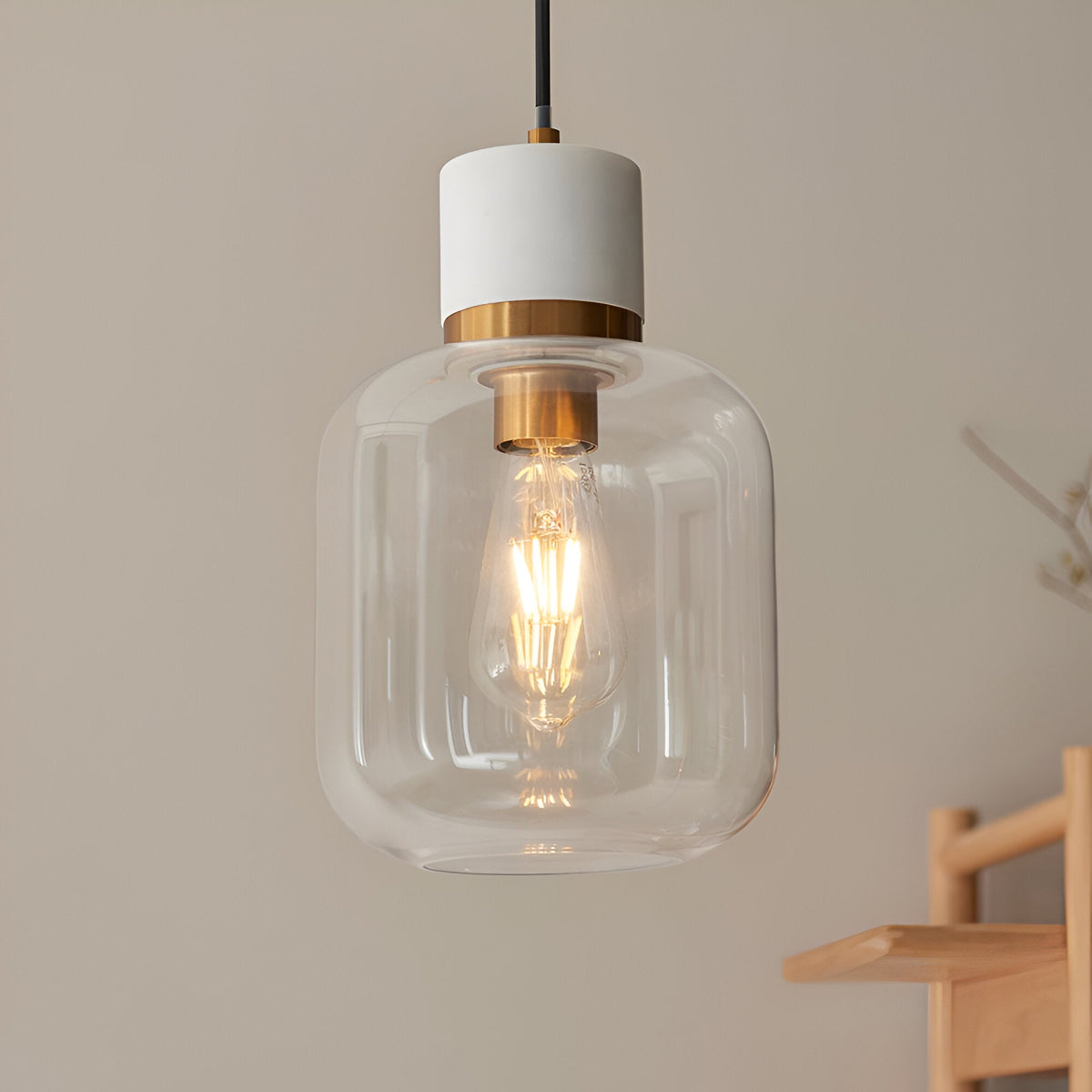 Endon Cranstead pendant light with white stone top, brushed brass collar and clear rounded glass shade housing an E27 filament bulb, hung indoors.