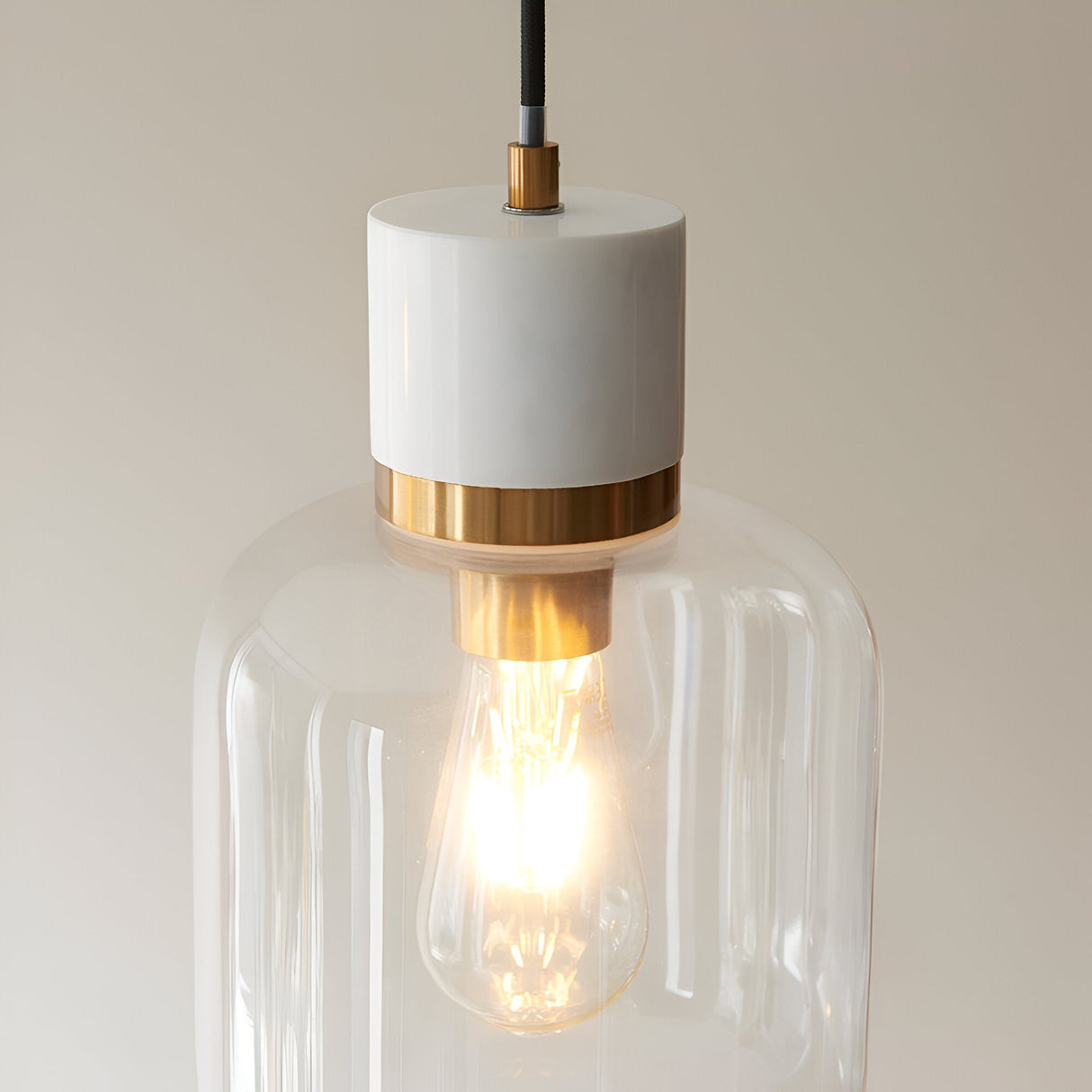 Endon Cranstead pendant light with white stone top, brushed brass collar, clear glass shade and lit E27 filament bulb on a neutral background.