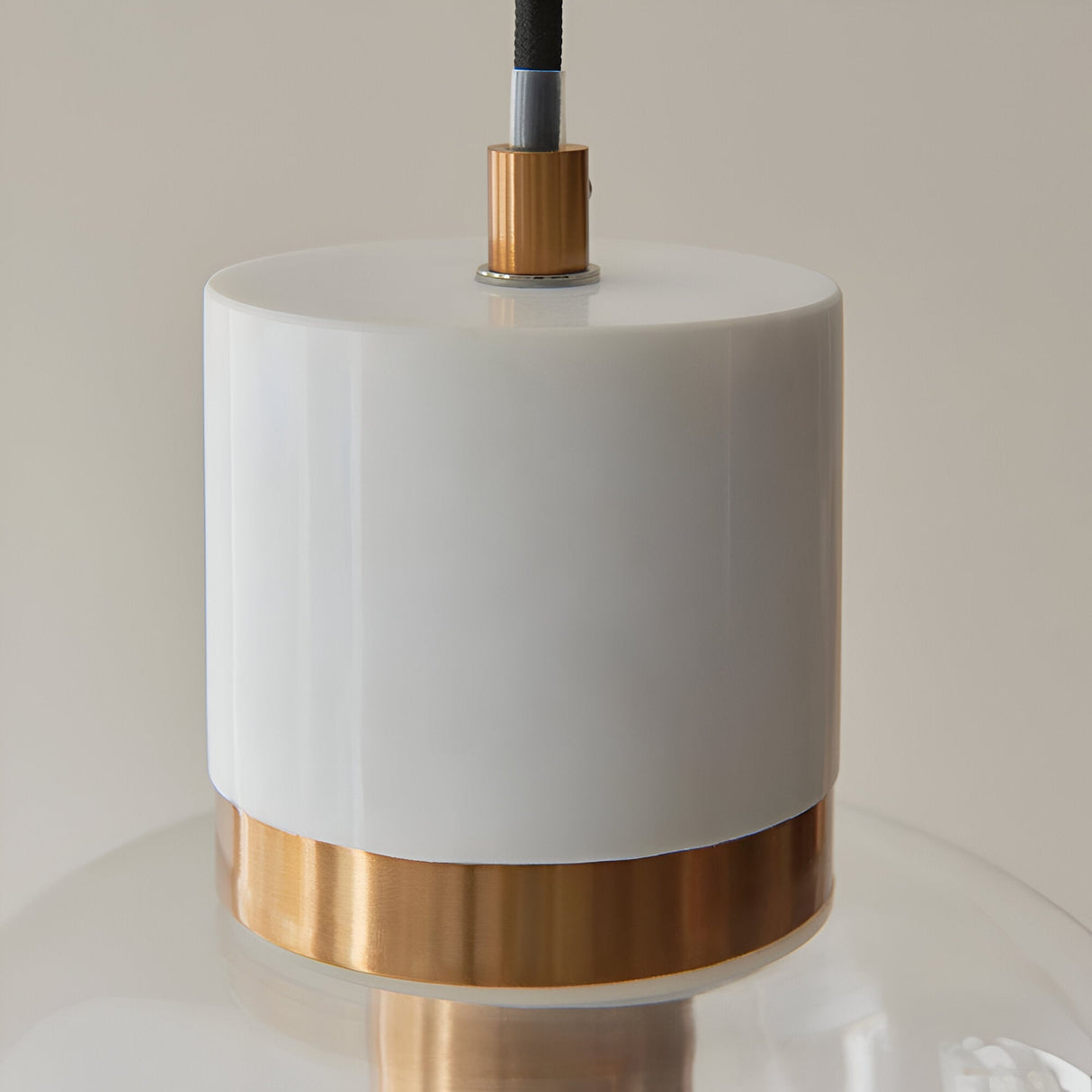 Endon Cranstead pendant light close-up showing white stone top, brushed brass collar and black fabric flex above a clear glass shade.