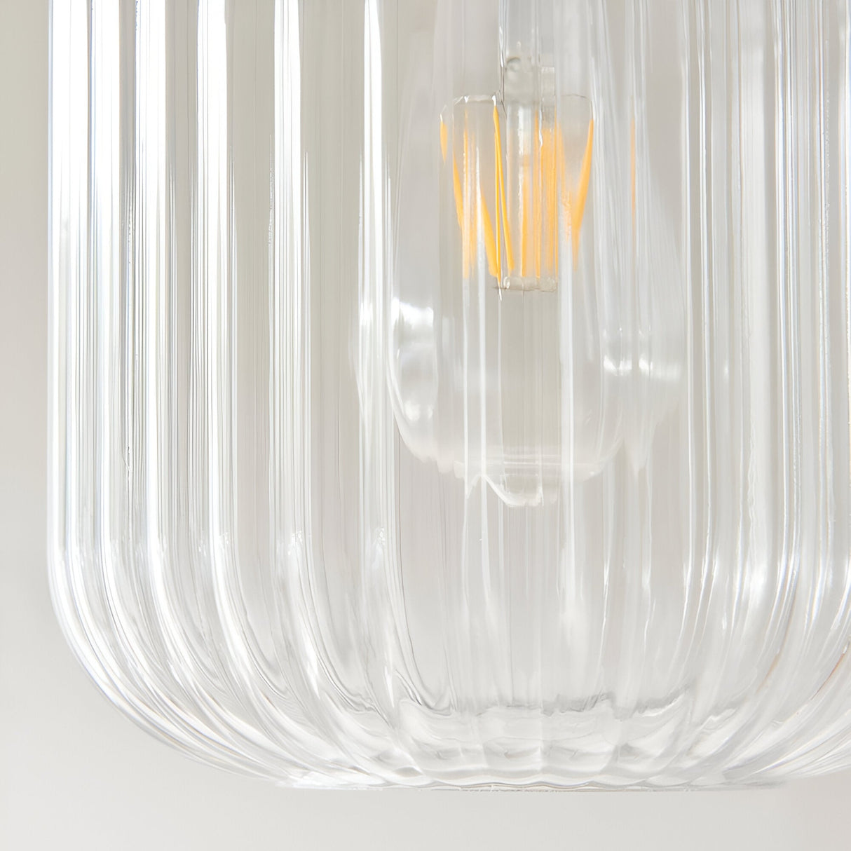 Close-up of the Cranton Pendant Light's ribbed clear glass shade with visible E27 filament bulb and brass fitting, on a plain light background.