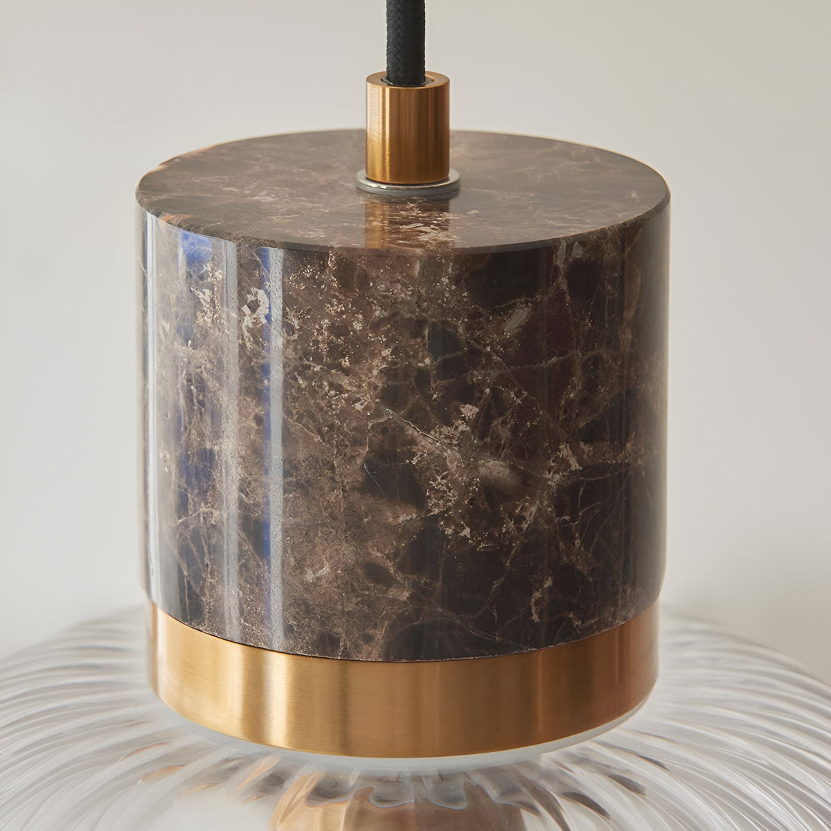 Endon Cranton pendant light close-up showing dark brown Emperador marble top, brushed brass collar and clear ribbed glass shade with black fabric flex.