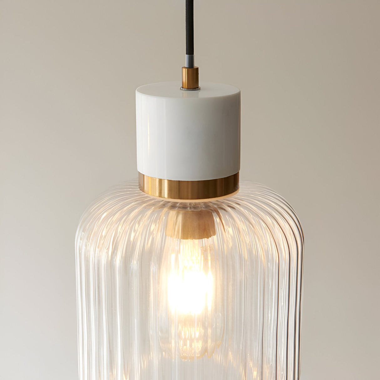Cranton Pendant Light in Brass & White, close-up of white stone top, brass collar, and ribbed glass shade with visible E27 bulb, on a plain background.