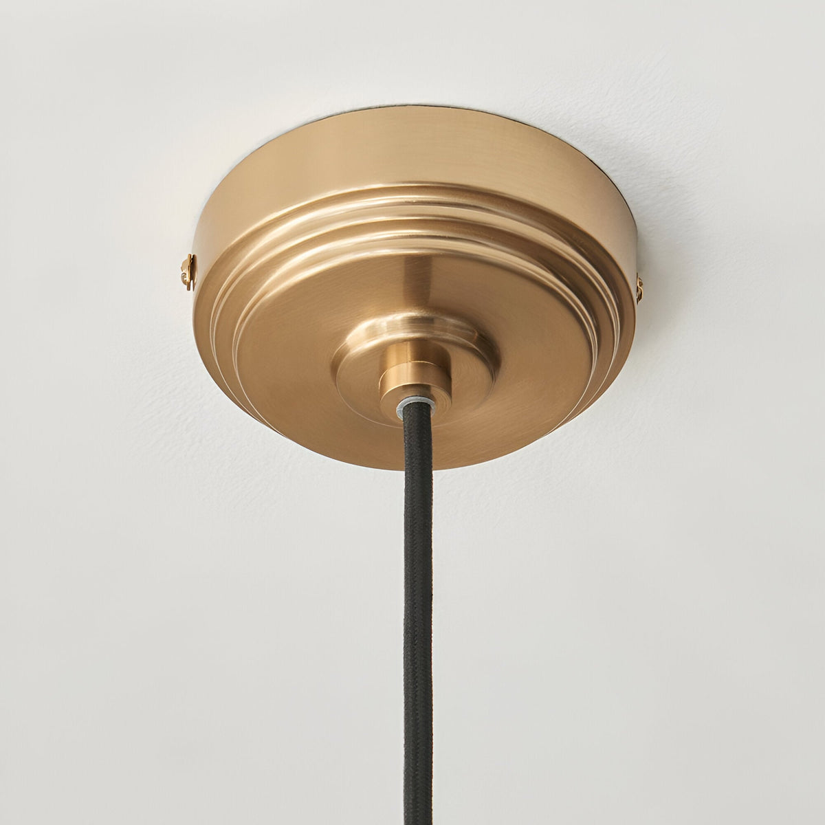 Brackmont Camellia Pendant ceiling canopy in brushed brass with black braided fabric cable, shown close-up against a plain white ceiling.