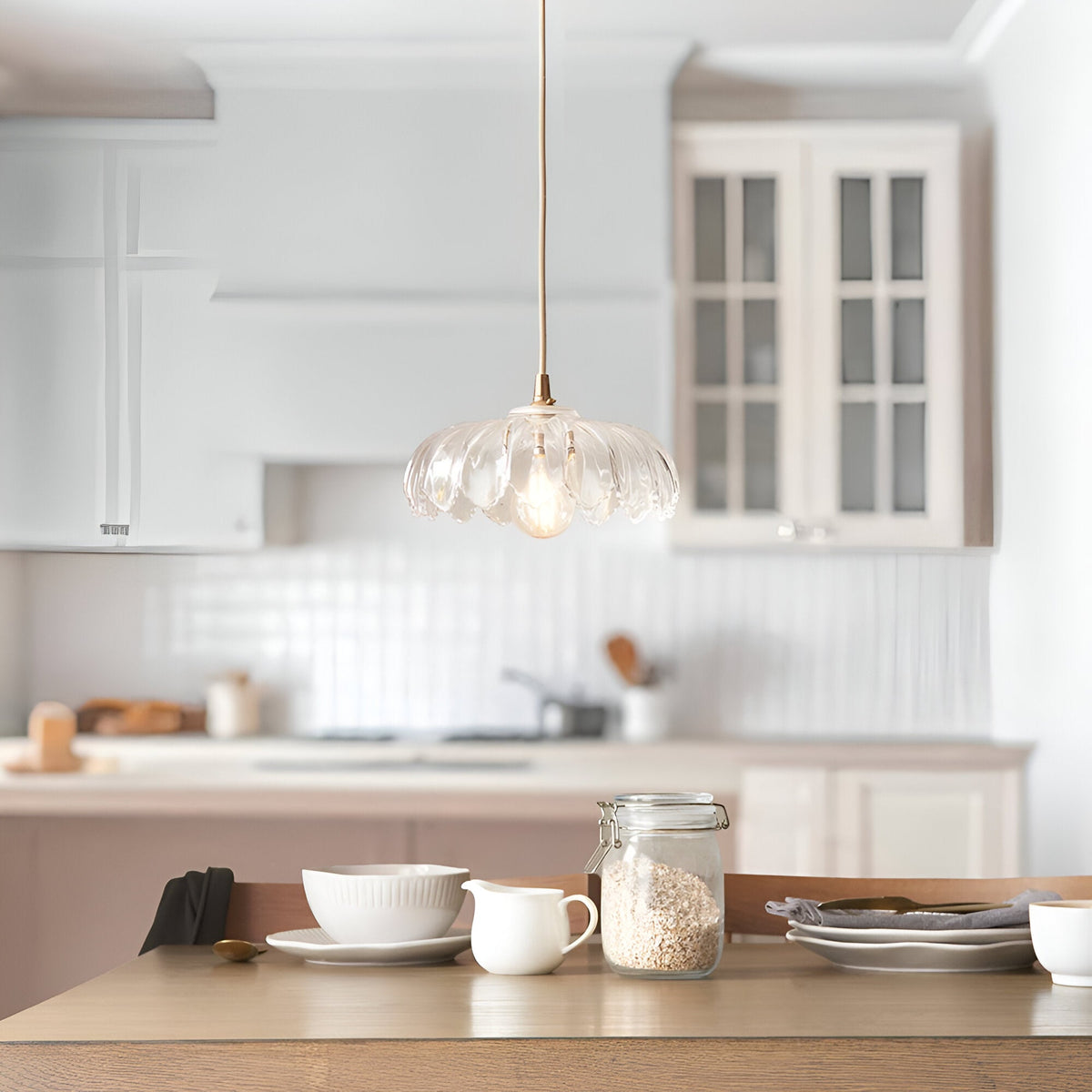 Brackmont Camellia Pendant with scalloped clear glass shade and brass fitting, hanging over a kitchen table with crockery and jars.