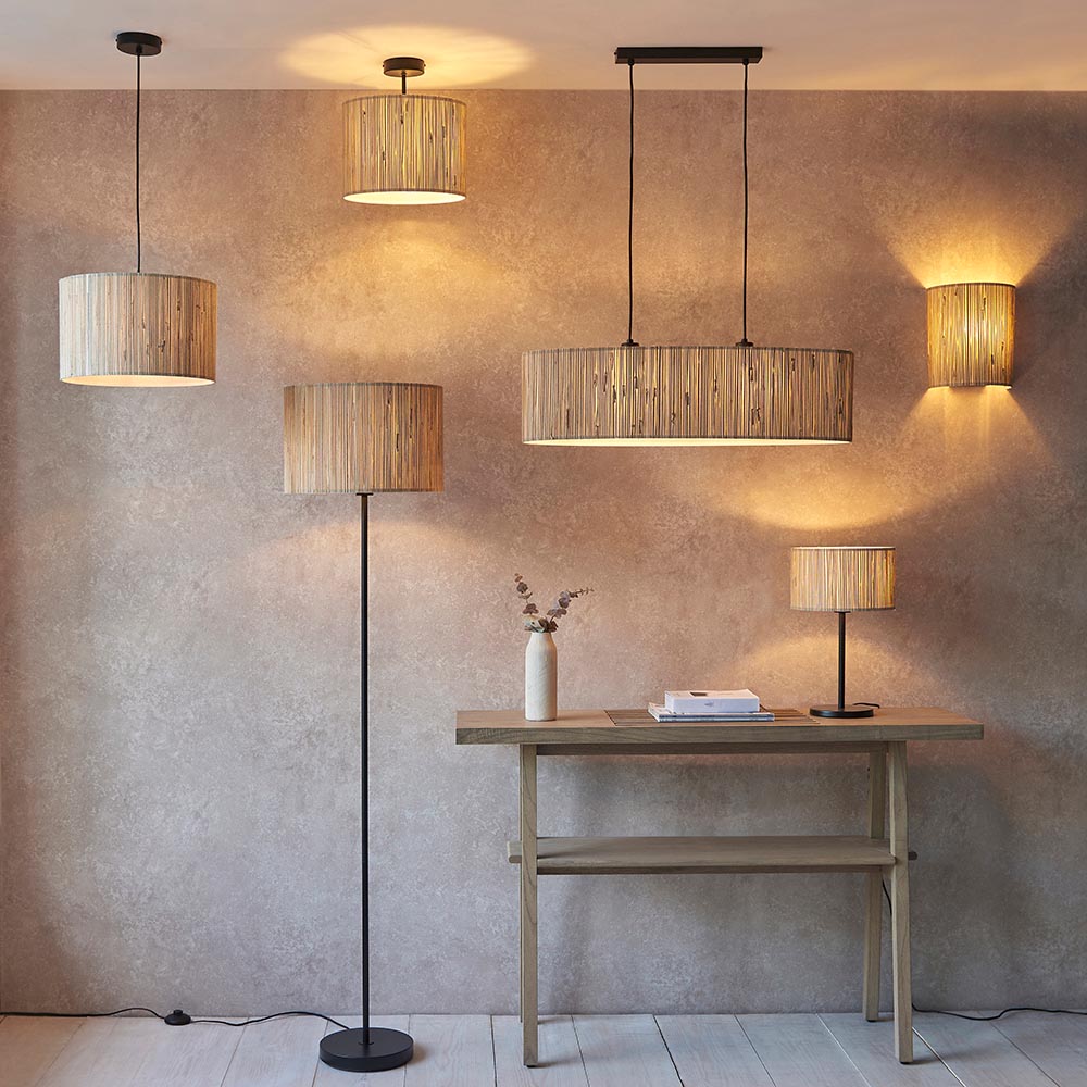 Salcombe Table Lamp with black metal base and woven seagrass drum shade, shown lit on a wooden desk in a lifestyle room setting.