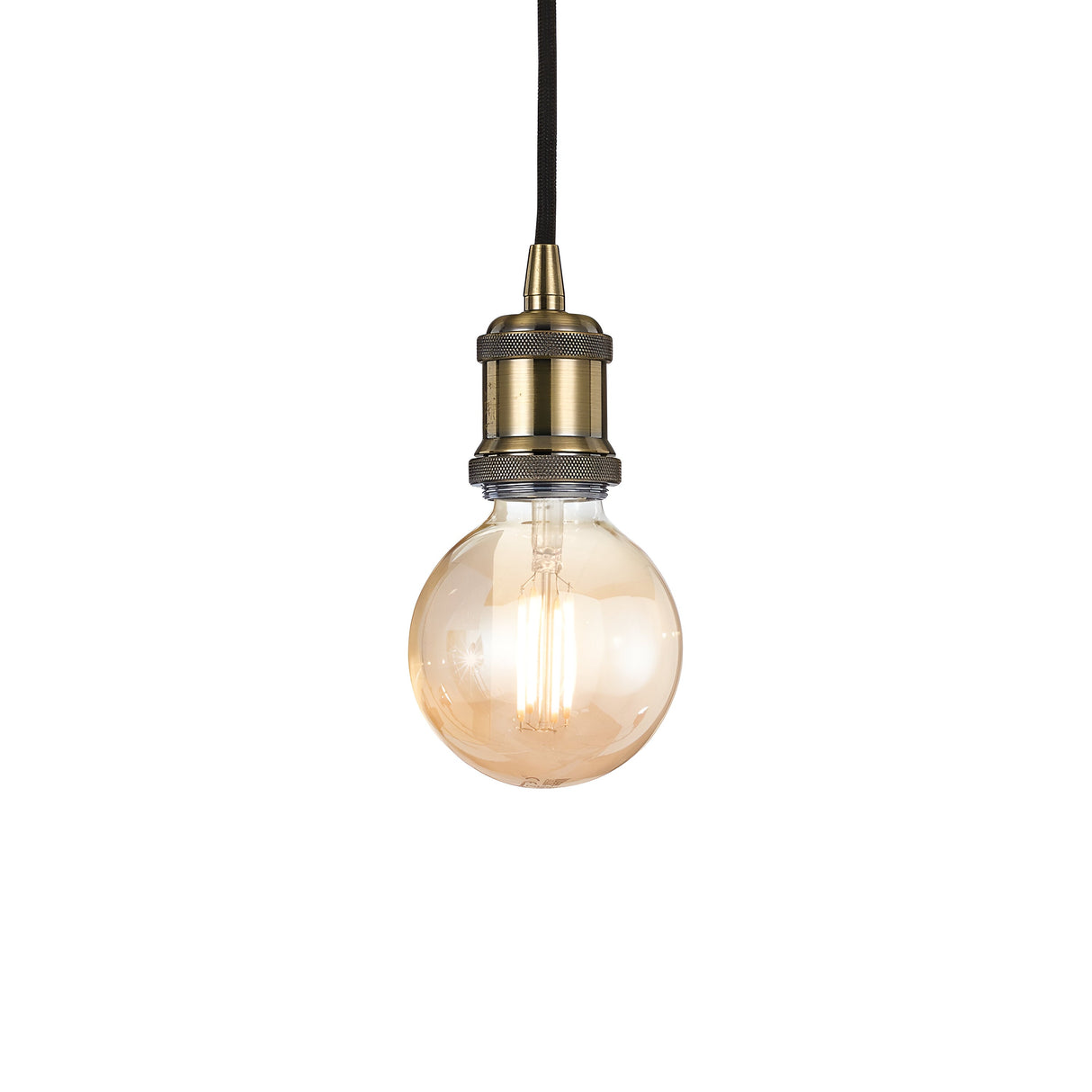 The Zip 1 Light Pendant - Brass features a vintage-style Edison bulb suspended from a sleek black cord, capturing modern minimalist design. Its warm glow subtly highlights the filament, creating a cozy atmosphere. The socket's antique brass finish enhances its industrial lighting appeal against a plain white backdrop.