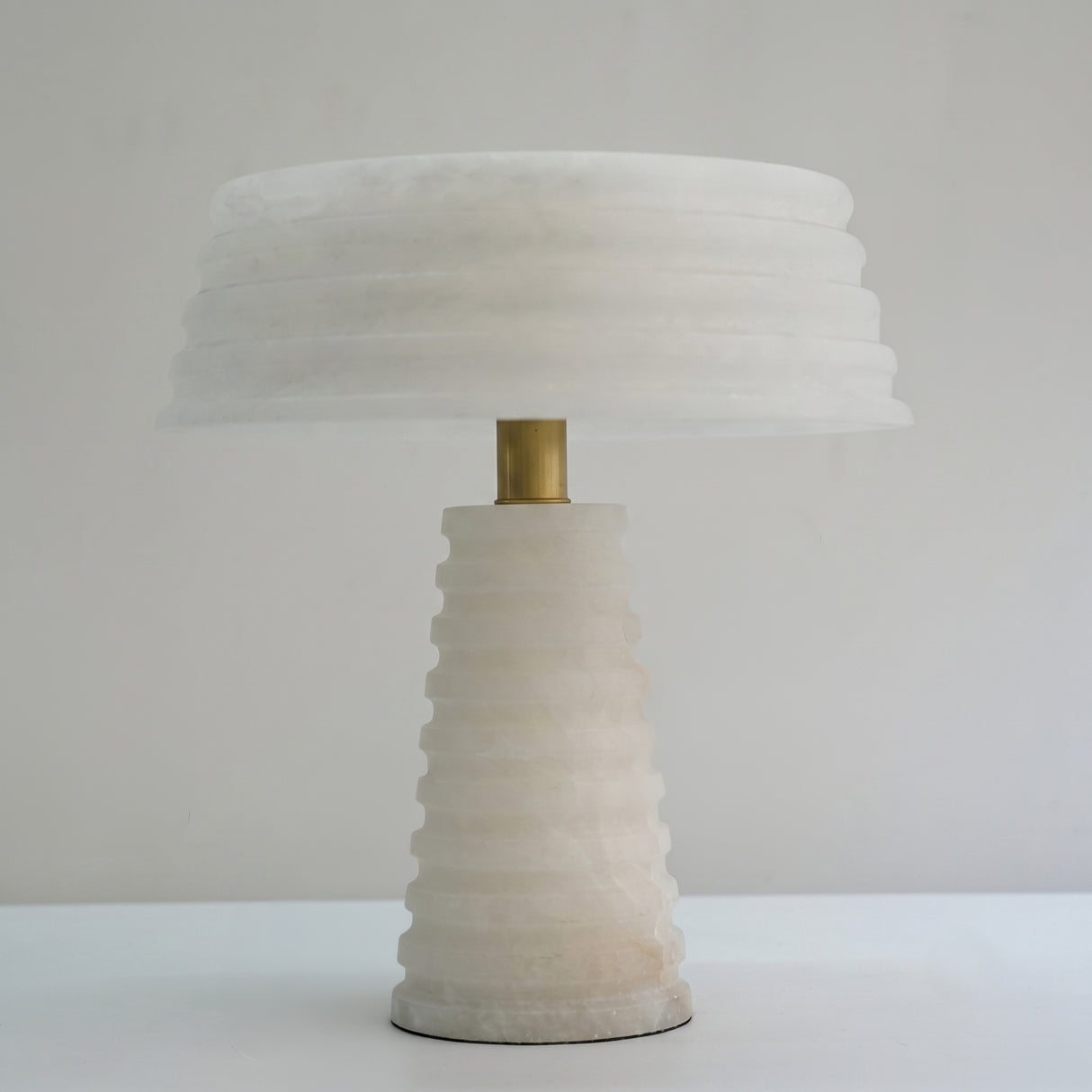 Orivon 3 Light Sculpted Alabaster Table Lamp in soft white, with ribbed tapered base, banded drum shade and brass finial, shown against a plain light background.