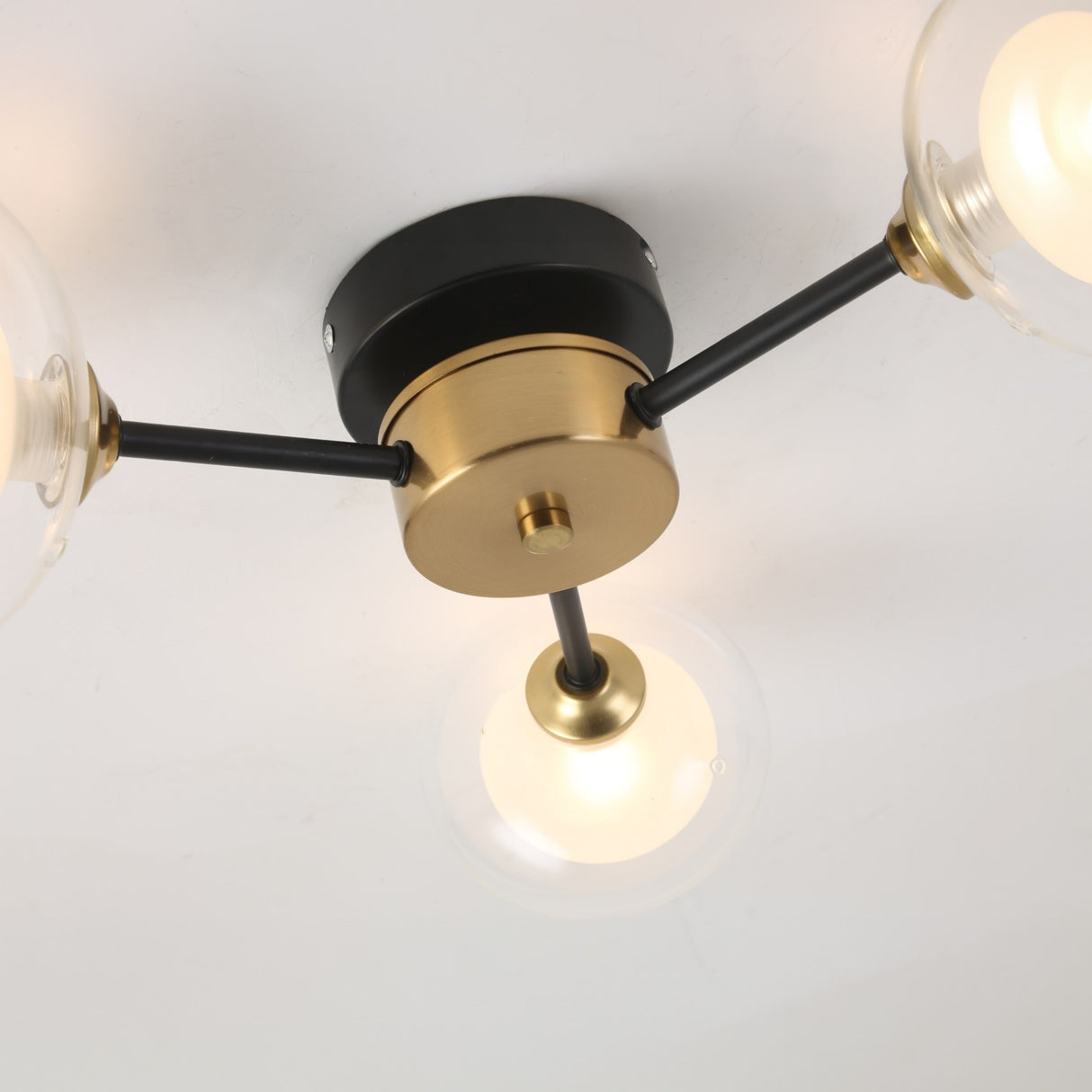 Close-up of the Galaxy 3 Light Wall/Semi-Flush Ceiling Light - Black & White, a modern fixture with three arms and frosted glass globe shades, mounted on a white ceiling for retro appeal.