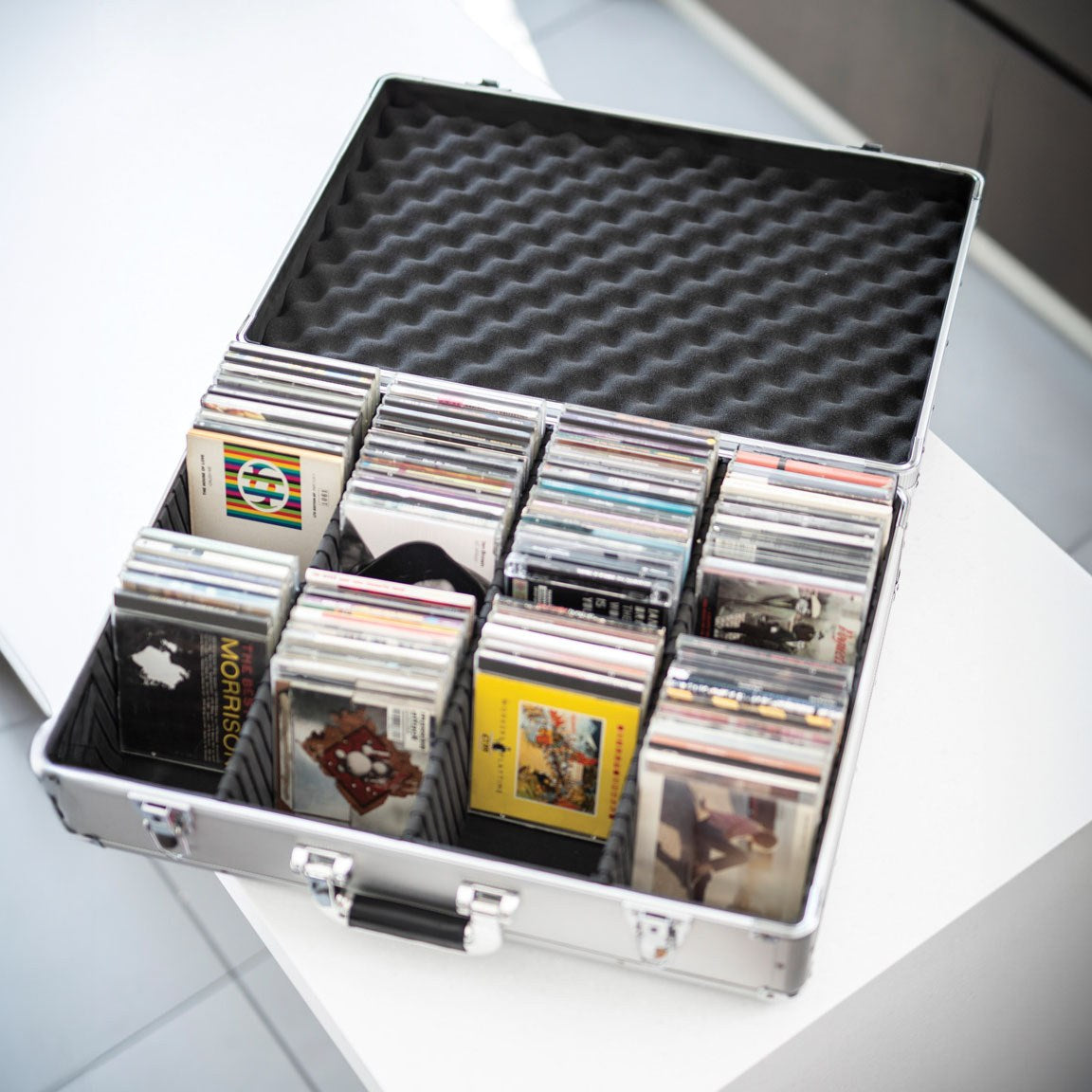 Citronic CDA:120 aluminium CD flight case open on a white surface, filled with CDs held upright by internal separators under a foam-lined lid.