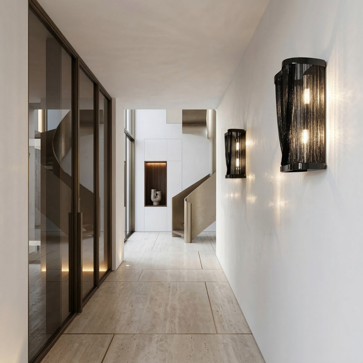 A modern, minimalist hallway with large beige floor tiles, glass doors on the left, Mireya 6 Light Metal Chain Veil Wall Lights in matte black on the right, and a sculptural staircase with contemporary wall art at the corridor's end.