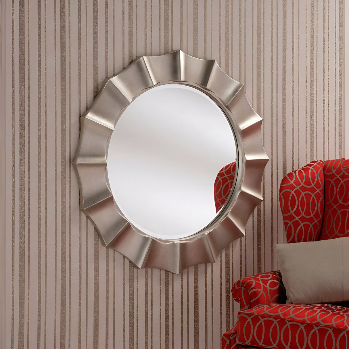 A Zenith Circle Wall Mirror Champagne - 104cm is elegantly displayed on a wall adorned with striped wallpaper. Nearby, a red armchair featuring a circular patterned design is partially visible, accented by a light-colored cushion for added comfort.