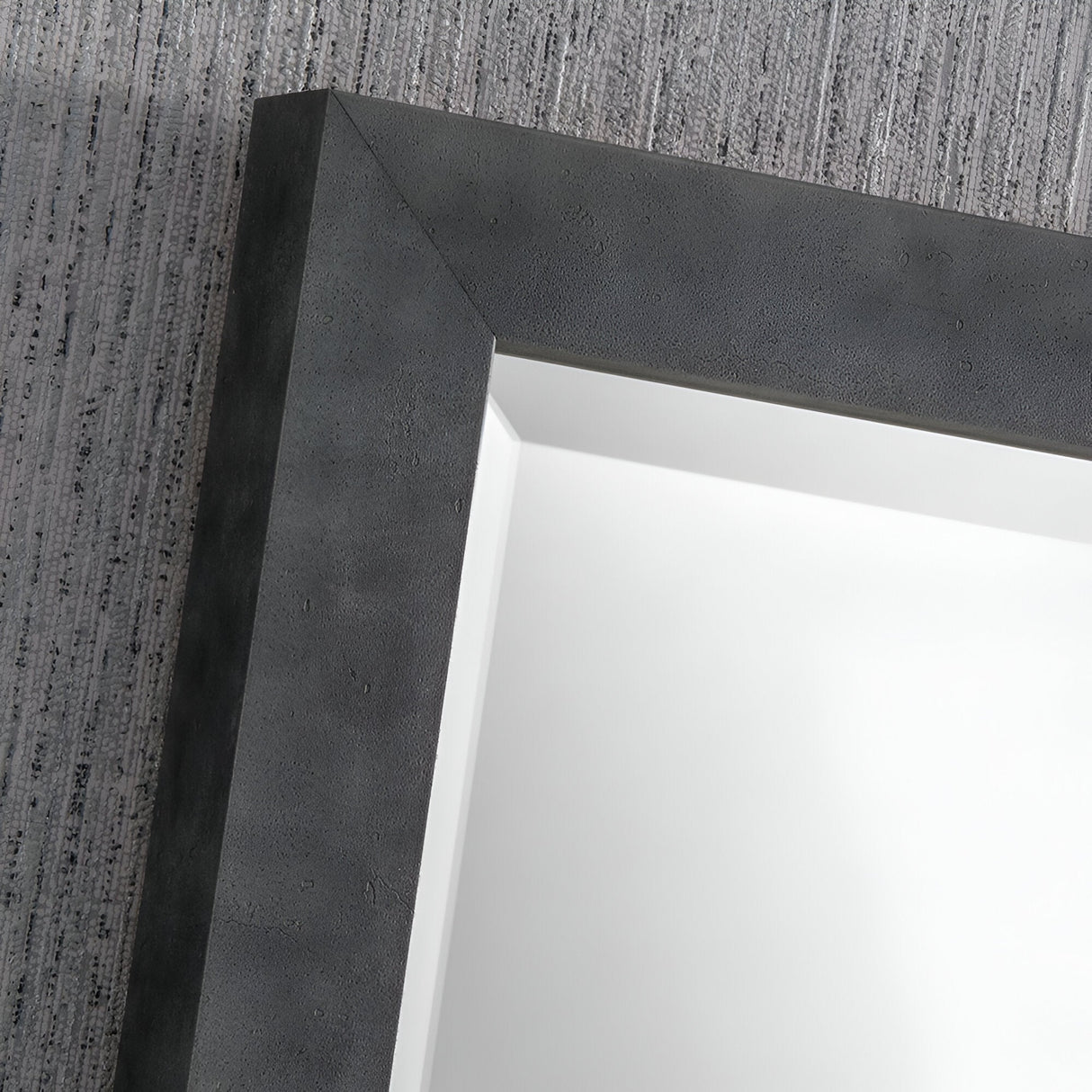 Close-up of the Echo Rectangle Wall Mirror - Dark Concrete, featuring a textured frame and mounted on a light gray, dark concrete wall, ideal for industrial-style interiors.