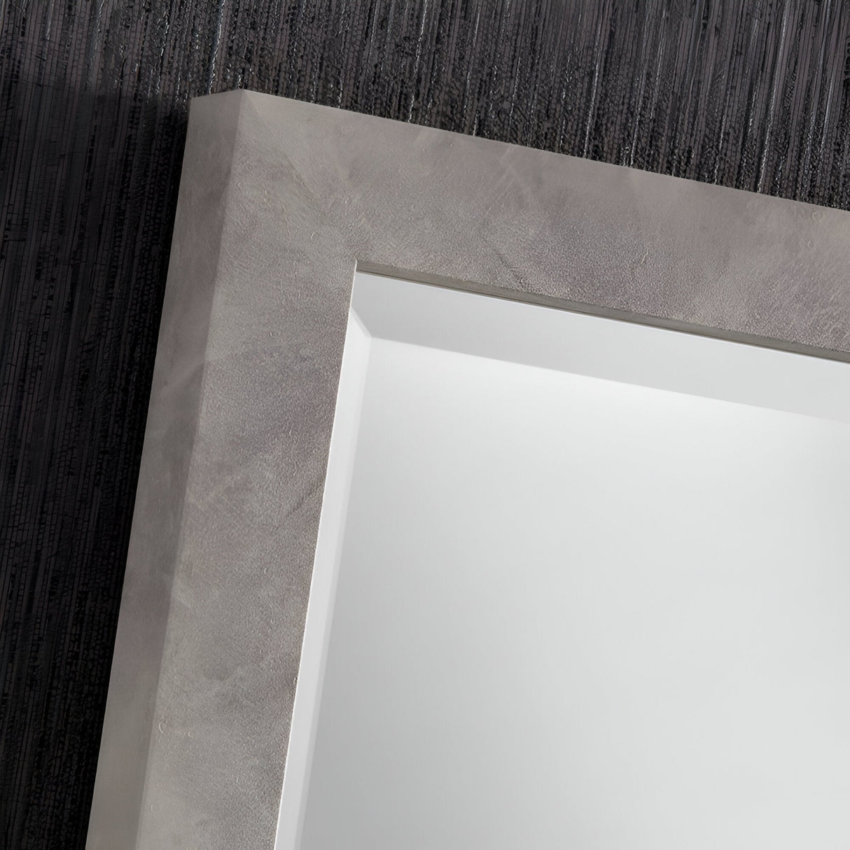 Close-up view of the Echo Rectangle Wall Mirror - Light Concrete set against a dark, ridged wall. The mirror reflects minimal light, highlighting its sleek and industrial design.