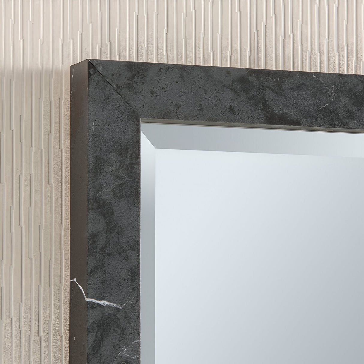 A close-up of the Eden Rectangle Wall Mirror - Dark Marble, showcasing its sophisticated frame with subtle white veining. Positioned against a textured beige wall with vertical lines, this elegant piece enhances any space.