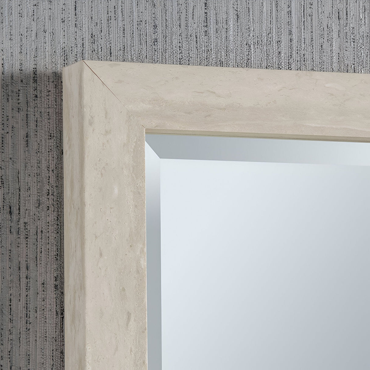 A close-up of the Eden Rectangle Wall Mirror in Light Grey showcases its textured, stone-like appearance. This elegant piece of home decor rests against a gray, vertically striped wall, highlighting modern sophistication where the frame seamlessly meets the mirror's surface.
