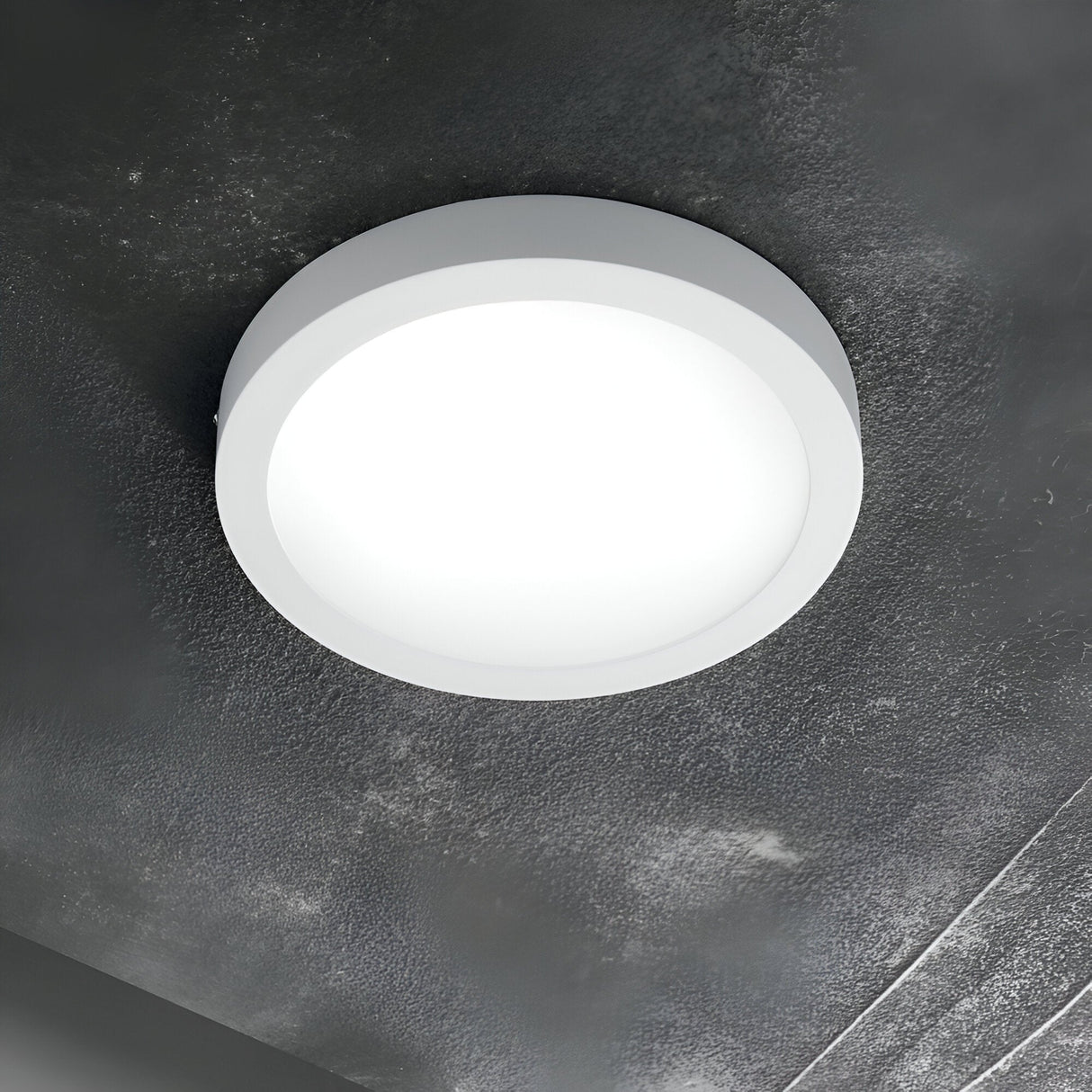 The Zephyrus Round LED Ceiling & Wall Light 19W 3000K - White, with its compact 22cm design, casts a bright, white glow against the textured, dark gray ceiling, enhancing its modern aesthetic.