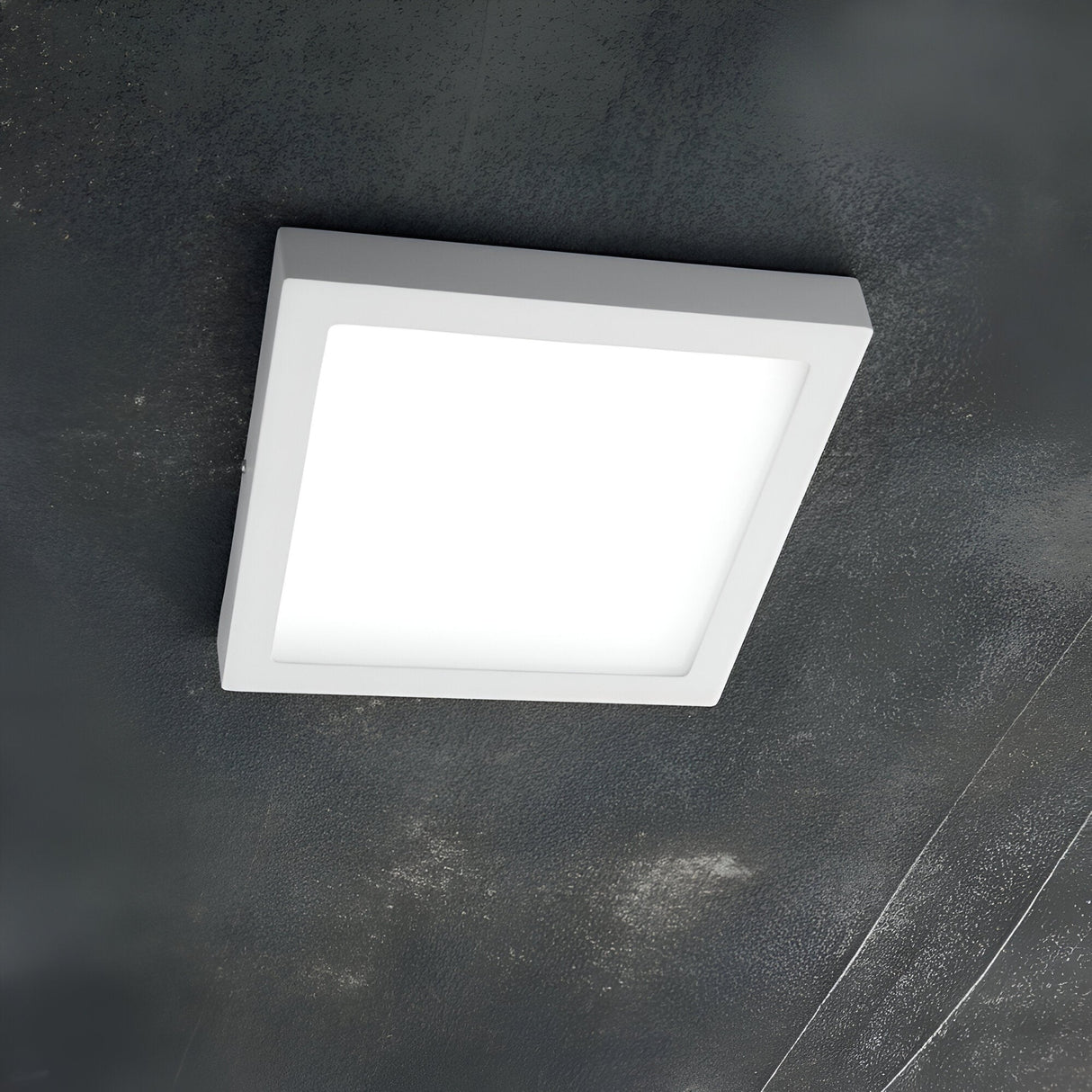 A Zephyrus Square LED Ceiling & Wall Light, measuring 22cm and emitting a soft glow at 3000K, is mounted on a textured dark ceiling.