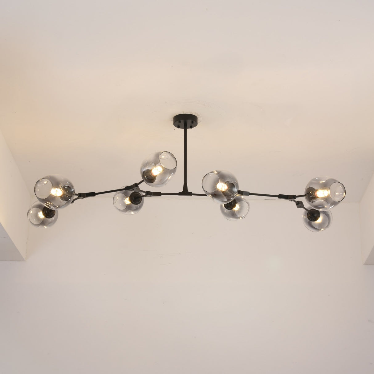 Niori Tree 8 Light Branching Suspension in matt black, mounted to a white ceiling with smoked glass globes lit warm along asymmetric arms.