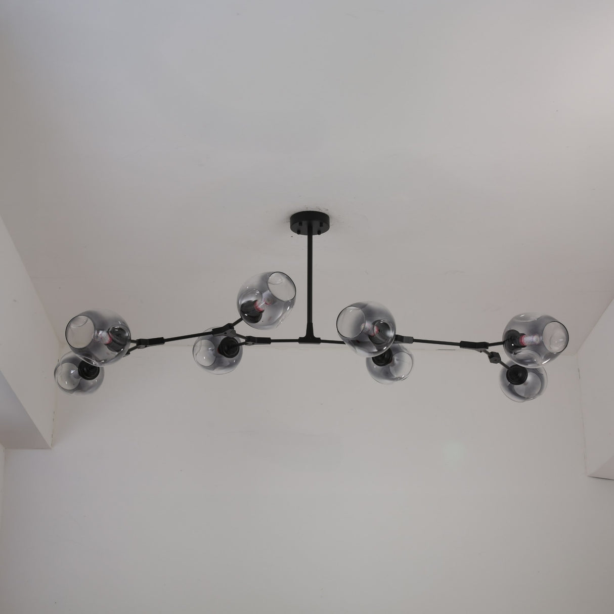 Niori Tree 8 Light Branching Suspension in matt black, viewed from below, with smoked glass globes on asymmetric arms mounted to a white ceiling.