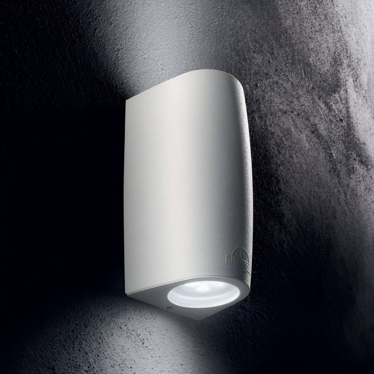 The Luz 2 Light Outdoor Wall Light in white, designed with high-performance resin, casts a soft glow on a textured gray wall, creating a contemporary and minimalist ambiance.