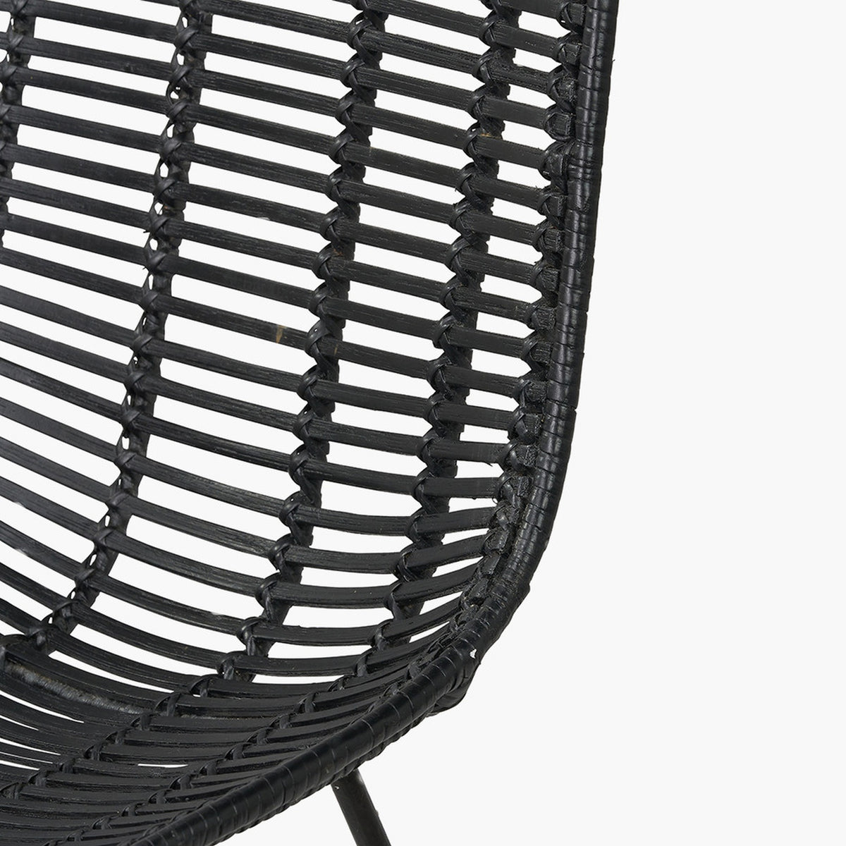 Close-up of the Black Rattan Core & Iron Dining Chair, showing woven rattan strands in a curved seat with black metal frame detail, set against a plain white background.