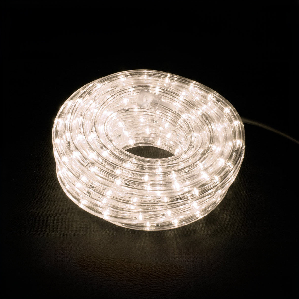 The LYYT 230V IP44 LED Rope Light, with its 50-meter length and 2800K warm white illumination, emits a soft glow against a dark backdrop. The lights are protected within a clear and flexible tube, creating an elegant circular shape that is also weather-resistant.
