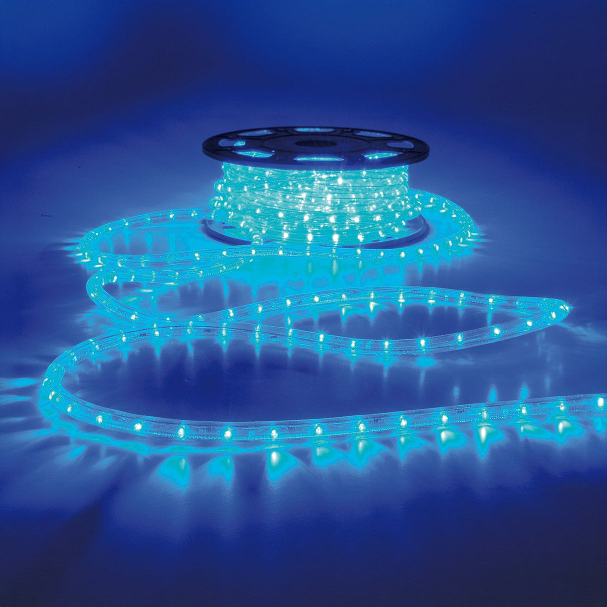 A spool of the LYYT 230V IP44 LED Rope Light 50m in blue is unrolled on a reflective surface, creating a vibrant and colorful display against a dark blue background. These lights are ideal for outdoor use, as they are weather-resistant and built to withstand the elements.