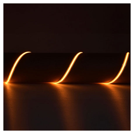 A series of glowing orange light trails, crafted with the LYYT 24V COB Strip Light 5m - 2000K technology, curve gracefully in a dark space, providing seamless 'no spot' illumination for a dynamic and abstract visual effect.