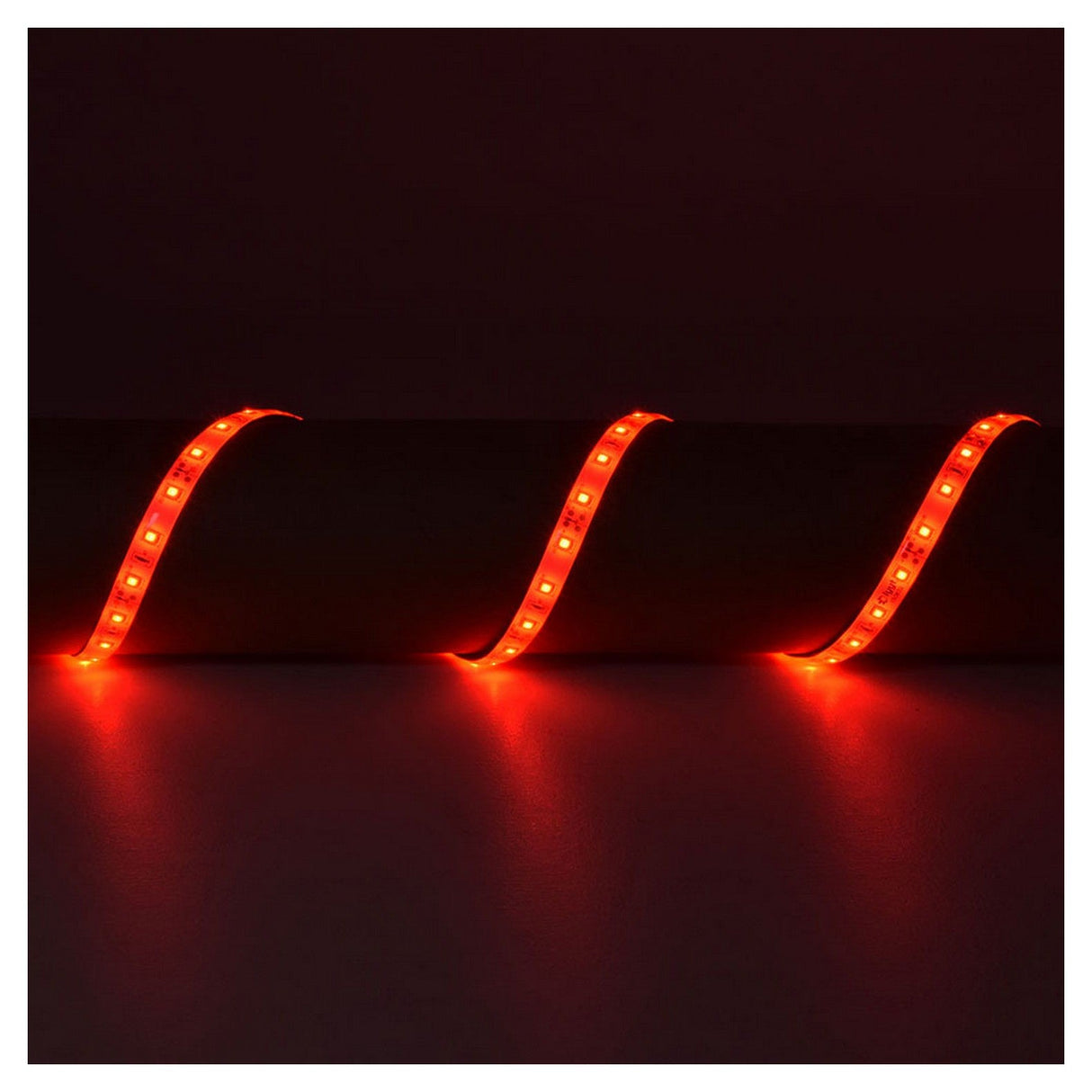 A dark room features the LYYT 12V LED Strip Light 5m - Red, with its super-bright LEDs illuminating in a vibrant red hue and creating a wavy pattern against a dark surface.