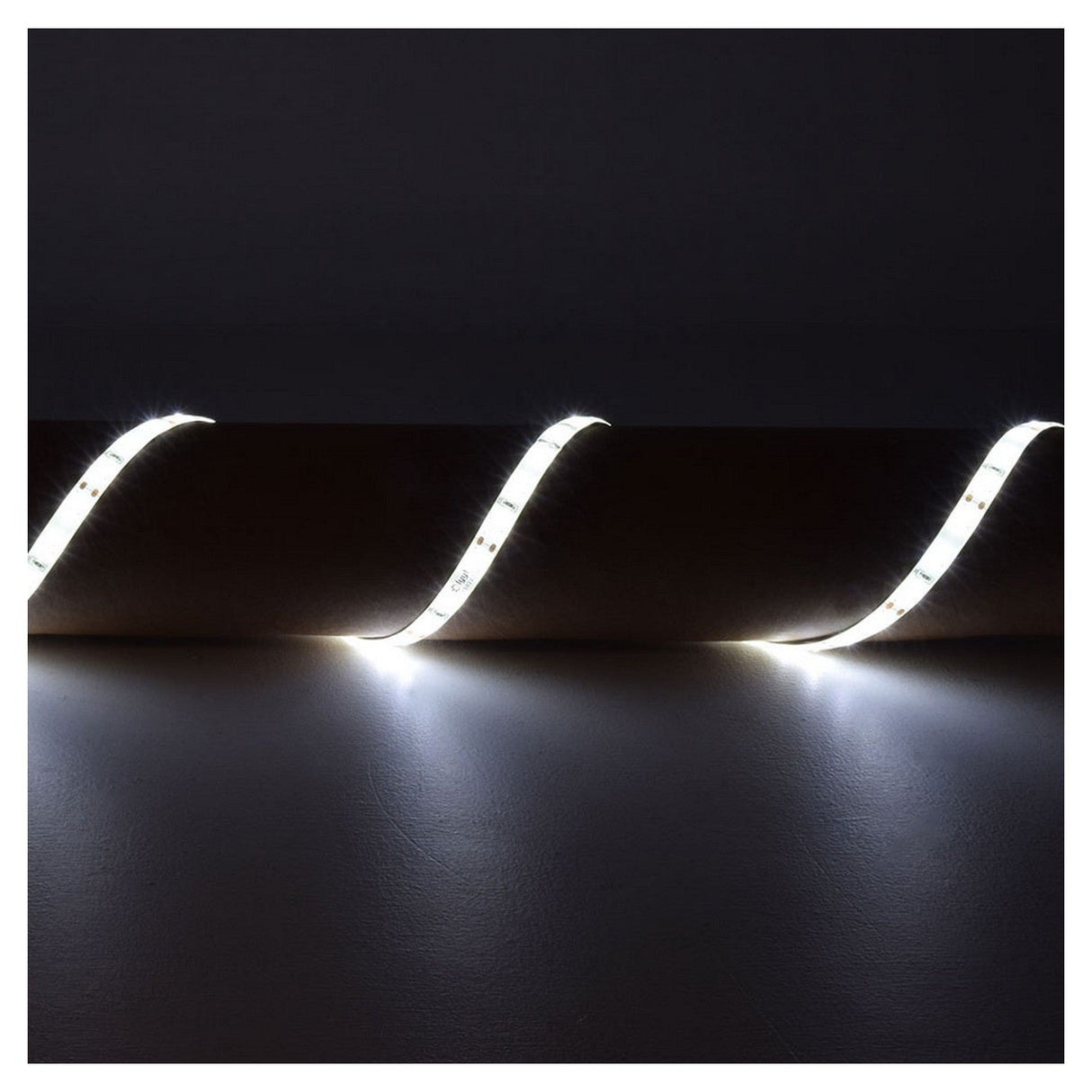 In a dimly lit room, the LYYT 12V SMD2835 Strip Light 5m - 6000K is installed along the top edge of the wall in a wavy pattern, illuminating the wall below with its soft, energy-efficient glow.