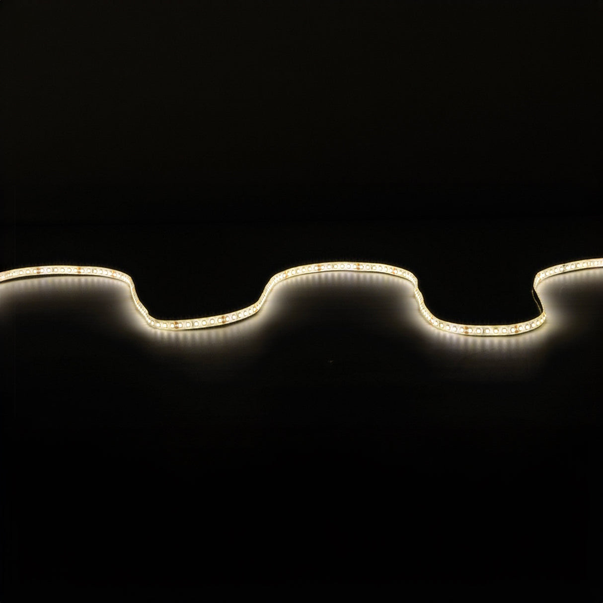 The LYYT 24V High Output LED Strip Light 5m - 3000K emits a gentle glow against a dark backdrop, forming an undulating line of light. Its high luminous flux accentuates the strip's curves and contours, offering warm illumination.