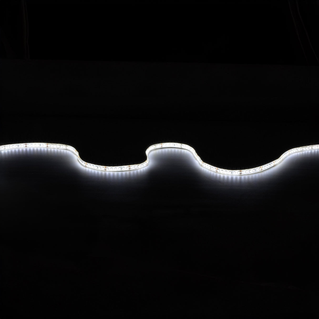 A wavy line of the LYYT 24V High Output LED Strip Light 5m - 6000K against a dark background creates a luminous, undulating pattern in the darkness, offering high luminous flux for optimal brightness.