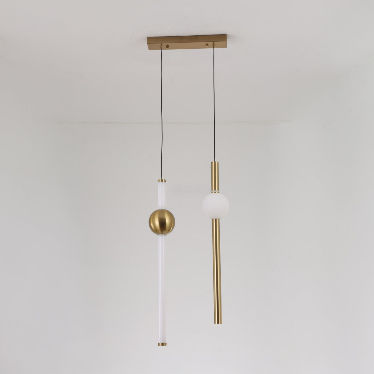 The Sottile LED Vertical Suspension Light - Gold features a modern minimalist design with two vertical rods—one white with a gold sphere and one gold with a white sphere—suspended from a gold rectangular ceiling mount for striking style.