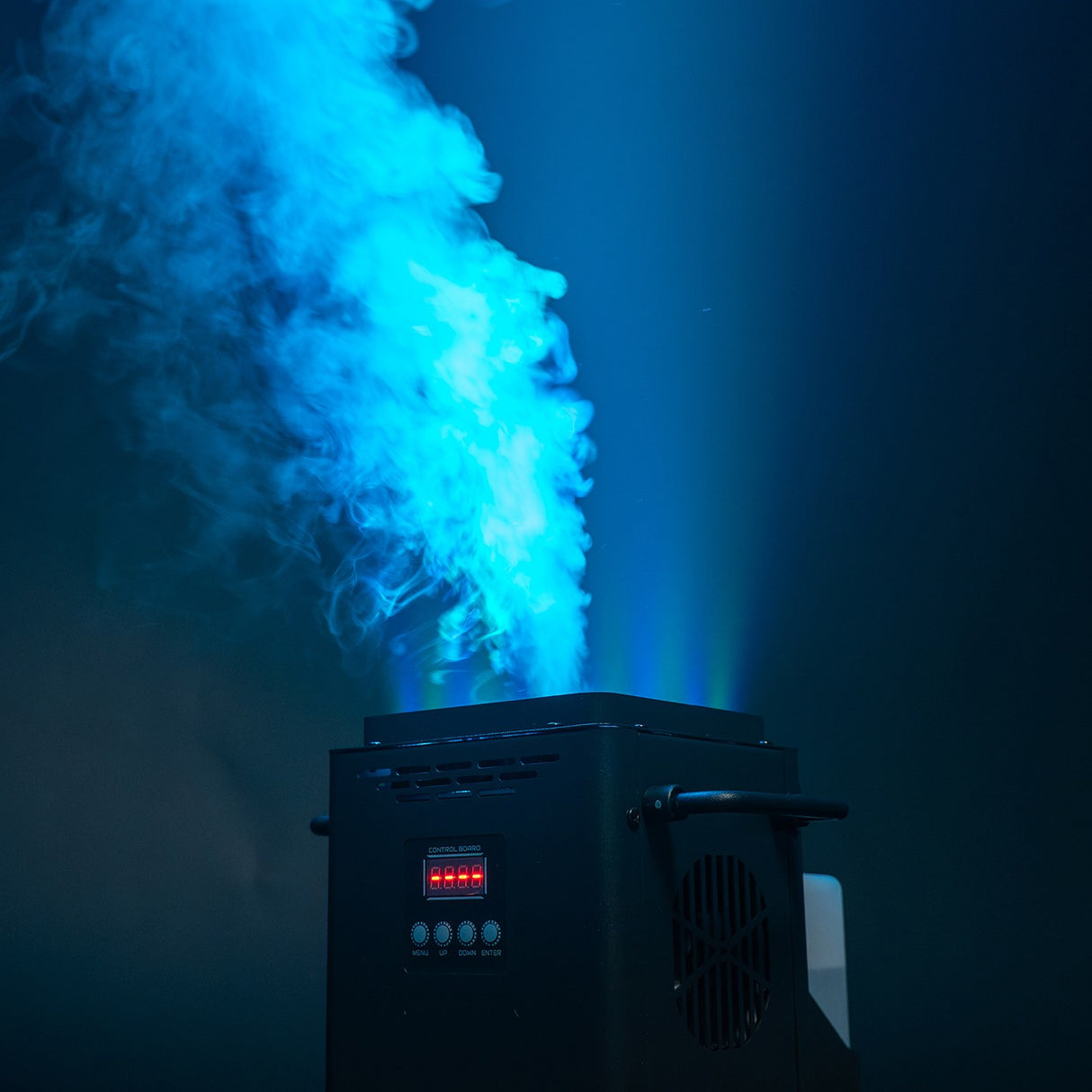 QTX VertiBox compact vertical LED fog machine by AVSL firing a tall jet of blue-lit fog upward, with LCD control panel and side handle visible.