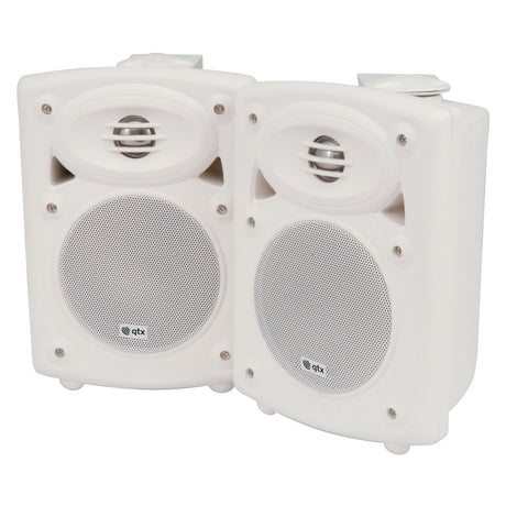 A pair of QTX QR5W 5" 20W Active ABS Speakers in white, featuring a compact, rectangular design. Each speaker includes a circular grille adorned with a small brand logo. Built-in amplifiers ensure these speakers provide deep bass response, and when positioned side by side against a white background, they easily blend into any setting.