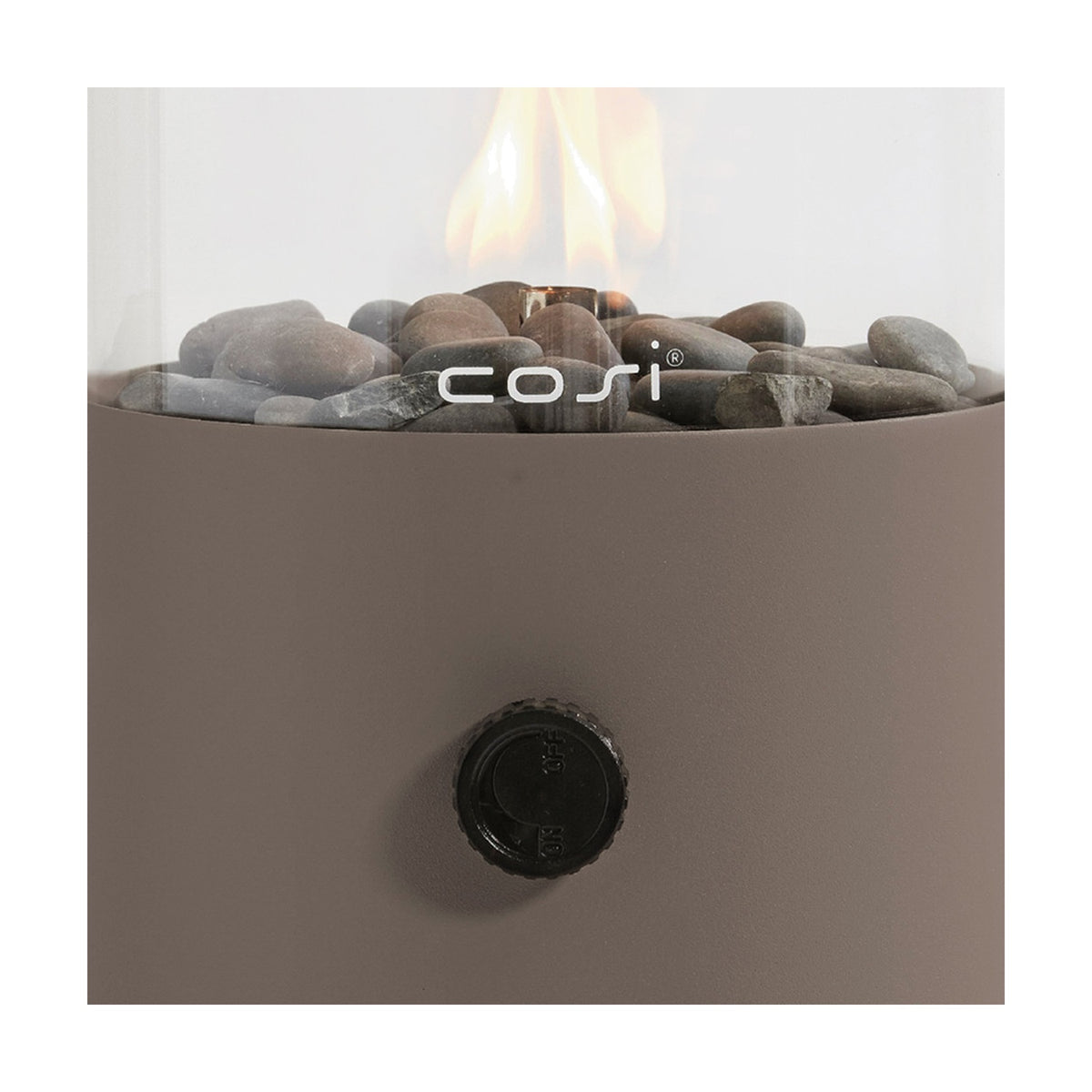 Close-up of the Cosi Clay Gas Flame Lantern, 30cm, showing the glass cylinder with lit flame over grey pebbles, a clay-coloured steel base, and black control knob.
