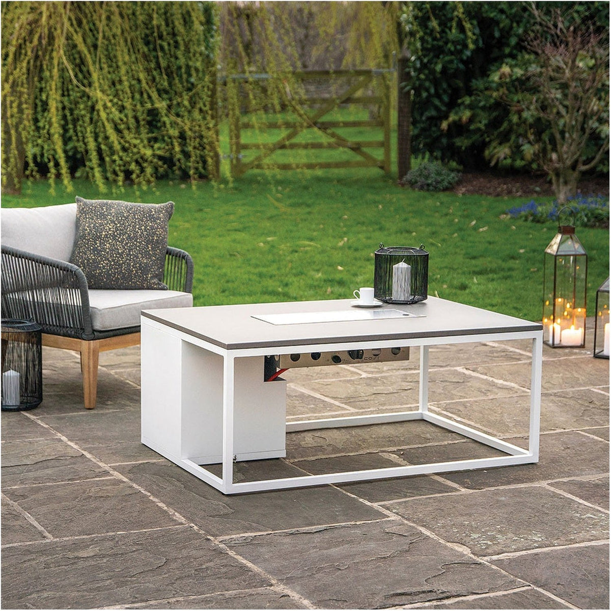 Cosi White & Grey Gas Fire Pit Table, 120cm, with white aluminium frame and grey tabletop, control panel visible, set on a patio in a garden setting.