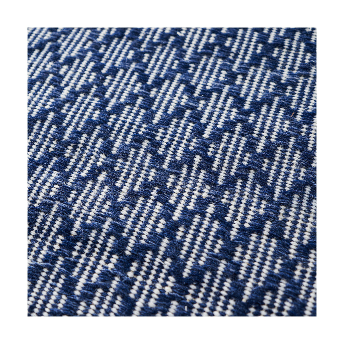 Close-up of the Indoor Outdoor Denim Blue & White Ikat Design Rug, showing a woven zigzag pattern in navy blue and white polyester.