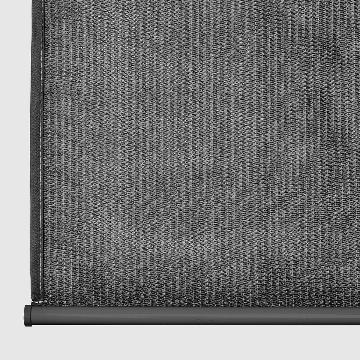 Close-up of a grey outdoor roller blind, showing the woven fabric texture, dark edge binding and lower roller bar with mounting bracket.