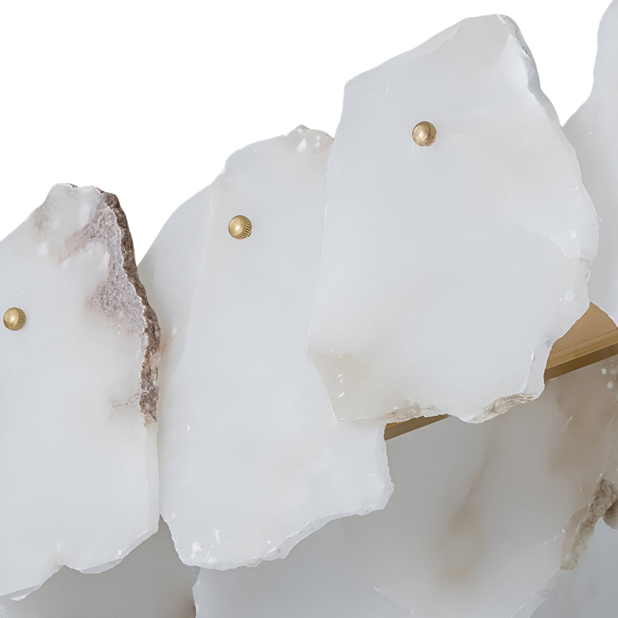Close-up of Niori Solvane alabaster linear chandelier showing translucent white petals with raw stone edges fixed to a brass bar by round studs.