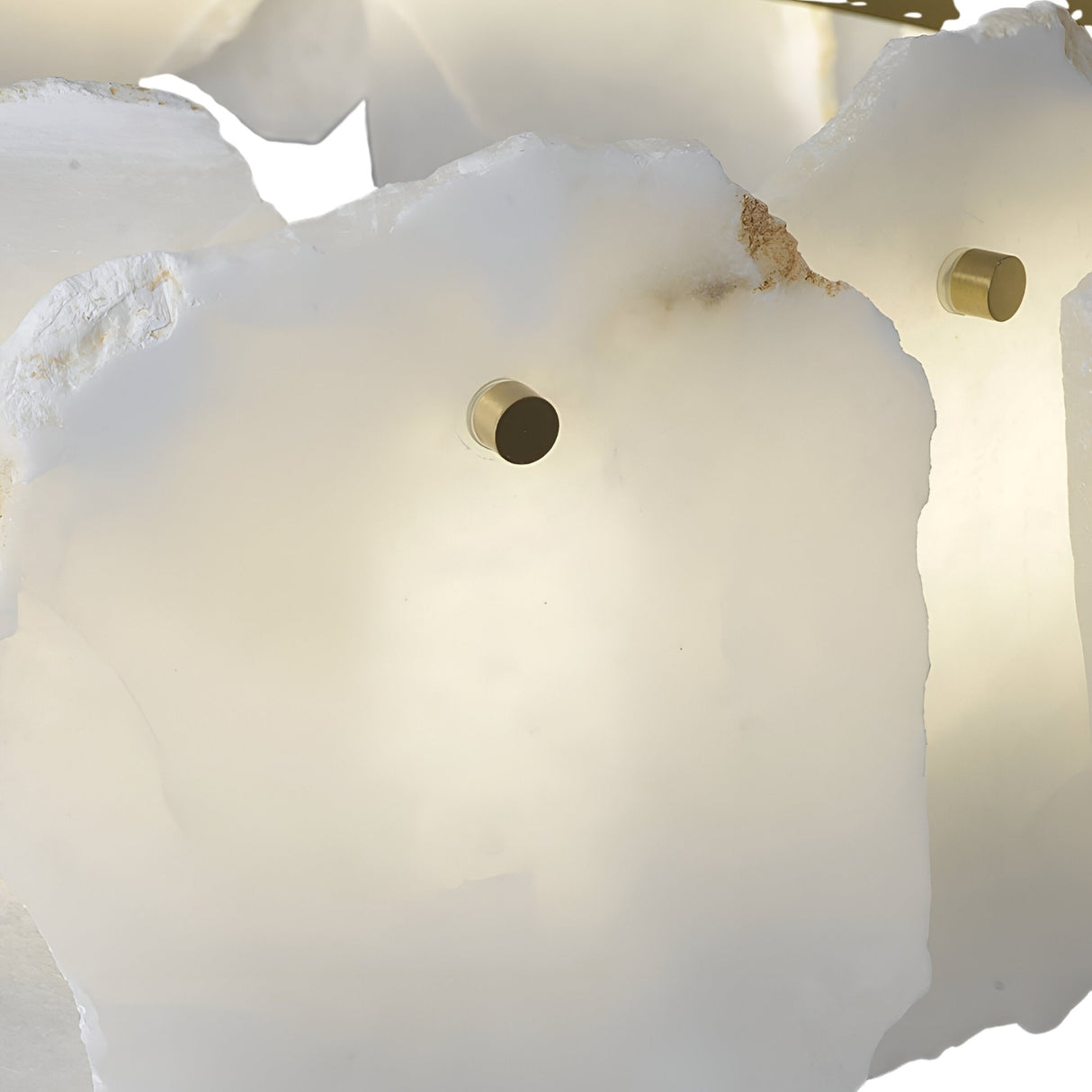 Close-up of Niori Solvane linear chandelier showing translucent Spanish alabaster petals with raw edges, brass fixings and warm internal LED glow.