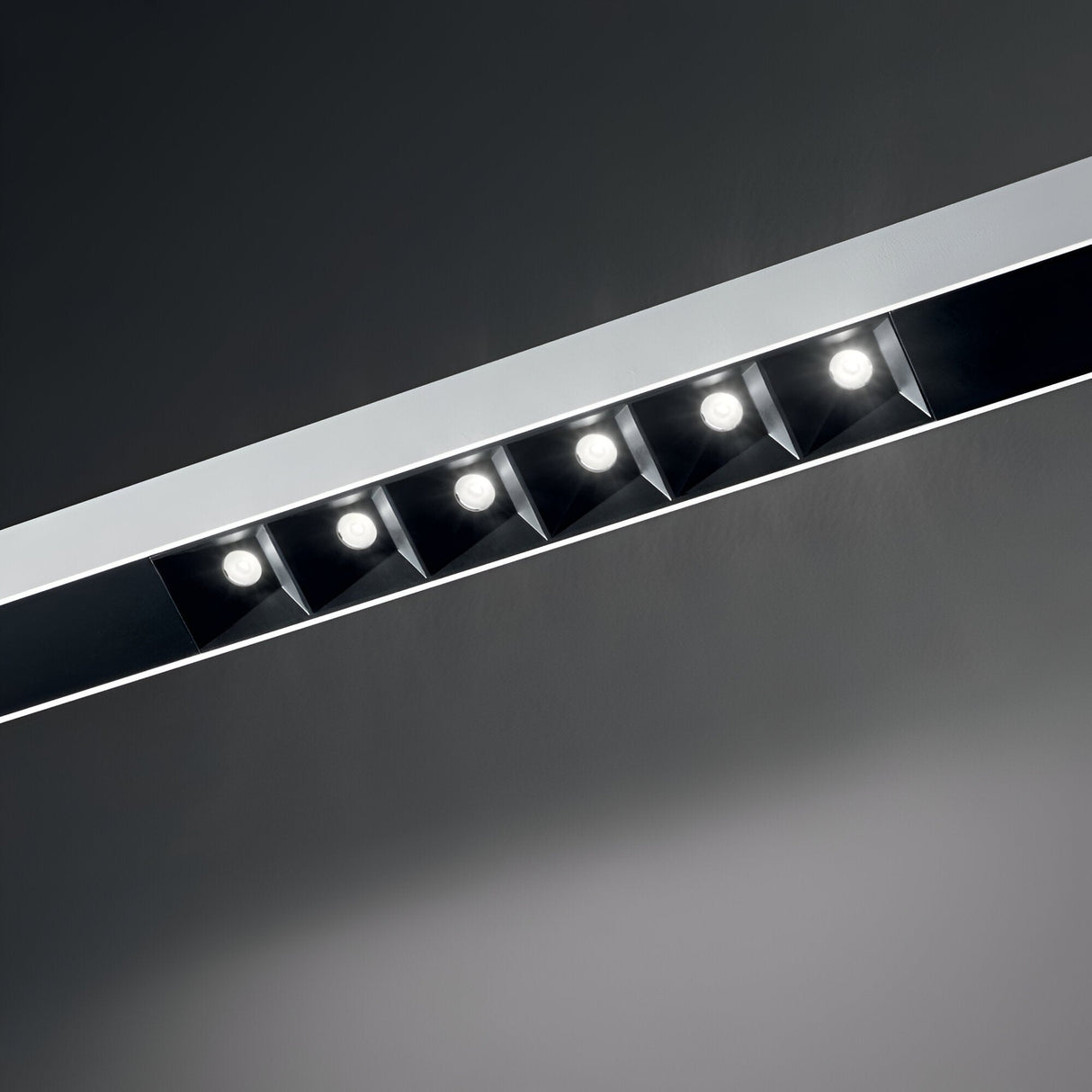 Introducing the Sparx Linear LED Suspension Light: A sleek ceiling fixture equipped with six energy-efficient LEDs, each set in individual reflective squares against a dark white background, delivering 30 watts of warm 3000K illumination across its impressive 1805mm span.