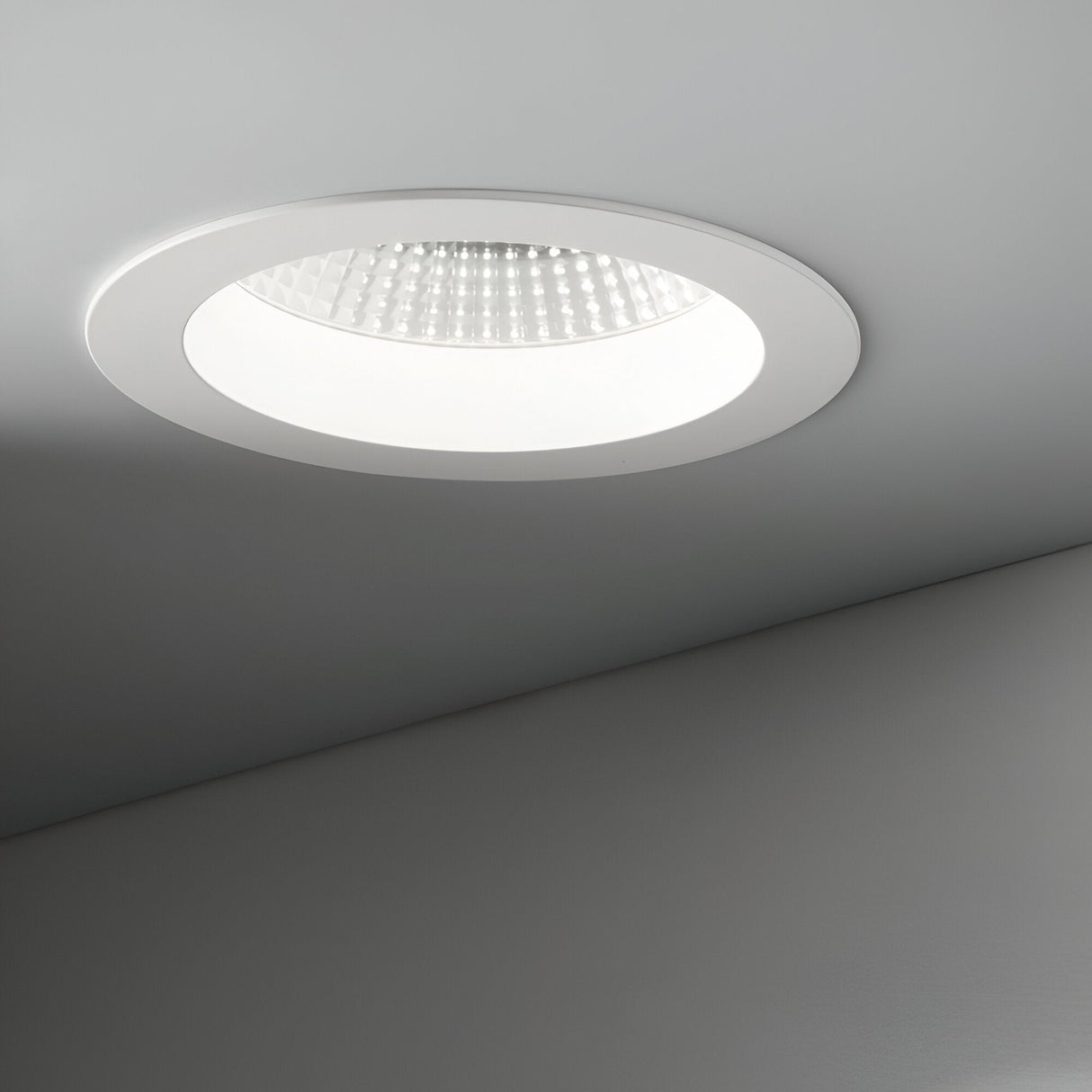 The Radiara-1 Round LED Recessed Downlight 71mm offers a clean, minimalist design while emitting a soft white glow at 3000K. Its energy efficiency enhances the simplicity, highlighting the smooth gray surface around it.