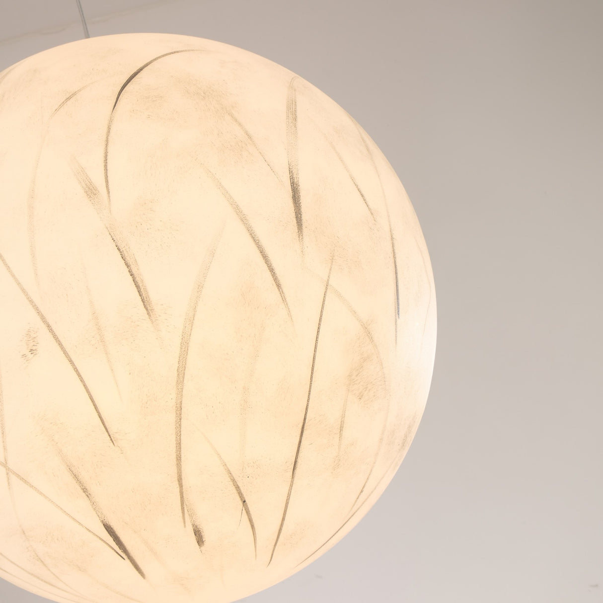 A close-up of the Lunar Flush Ceiling Light - White, a spherical frosted glass fixture with delicate curved patterns, set against a plain light background to create soft ambient lighting.