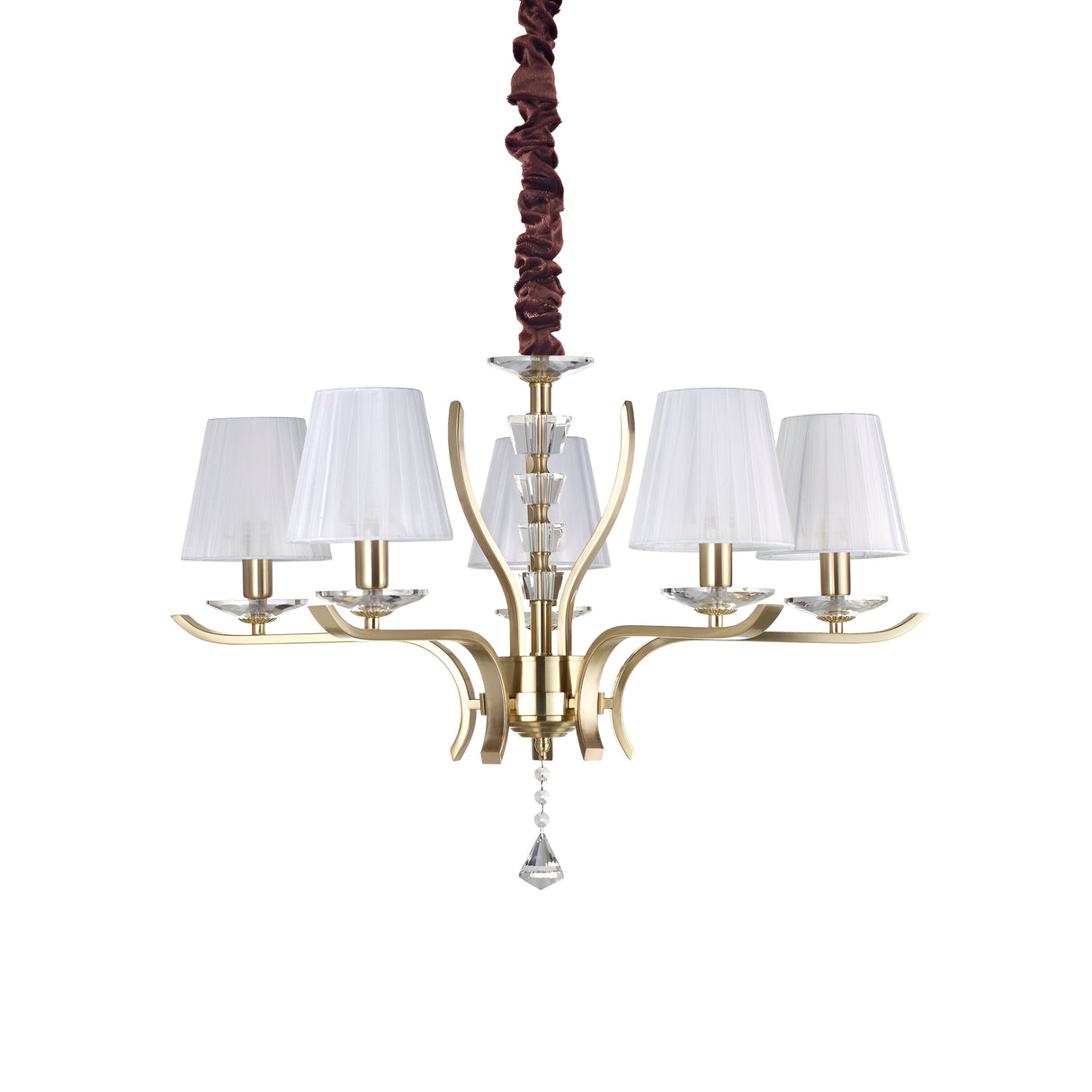 The Solum 5 Light Chandelier in brass hangs from the ceiling, featuring five organza lampshades. Its central design includes elegantly curved metal arms embellished with crystal pendants and a crystal ornament at the bottom, while a brown covering wraps around the chain.