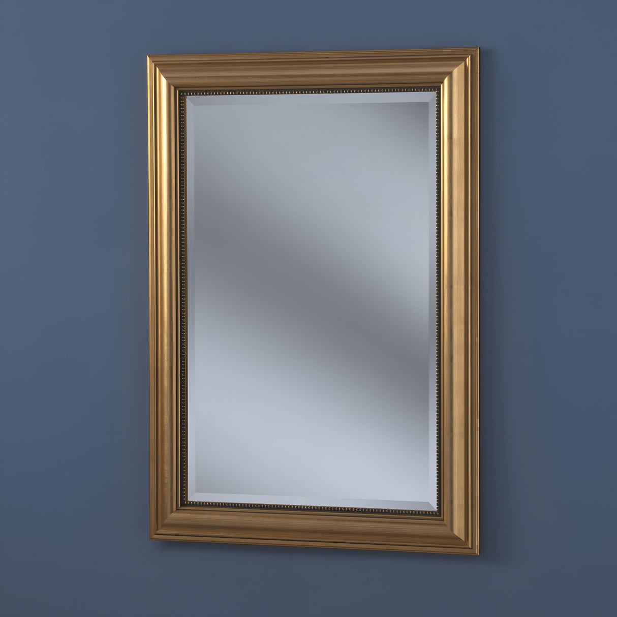 The Argentia Rectangle Wall Mirror - Gold, featuring an ornate frame, elegantly adorns a dark blue wall, ideal for stylish homes.