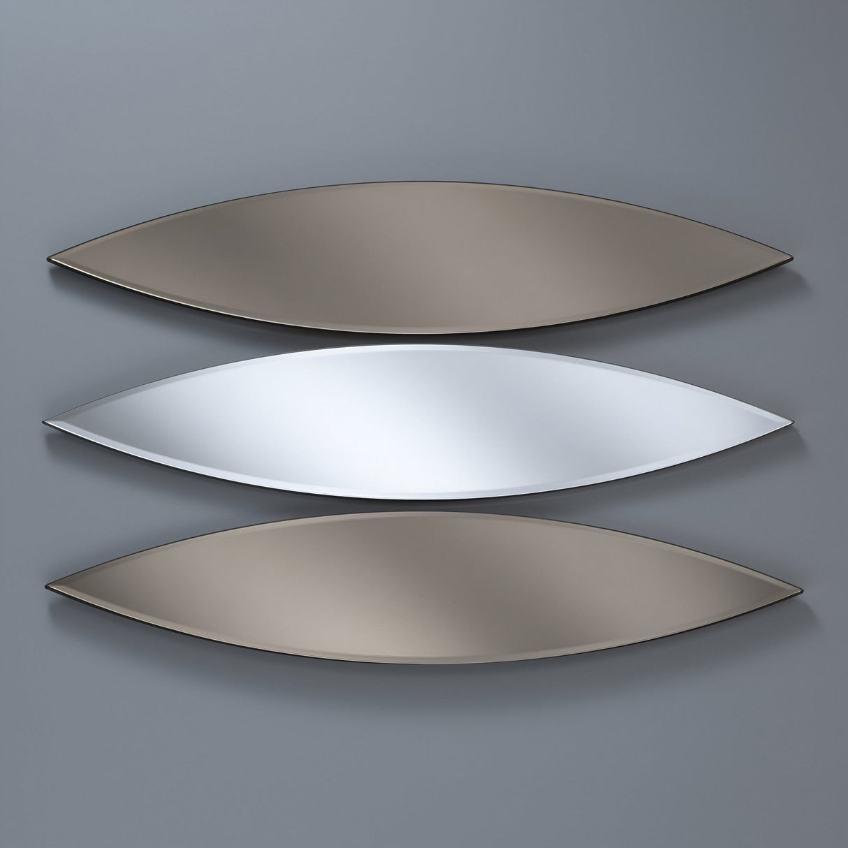 Three Aurora Oval Wall Mirrors (130x30cm) in a pointed-end design are mounted horizontally on a gray wall; the center shines in silvery tones, while the top and bottom feature a dual-tone bronze and silver finish.