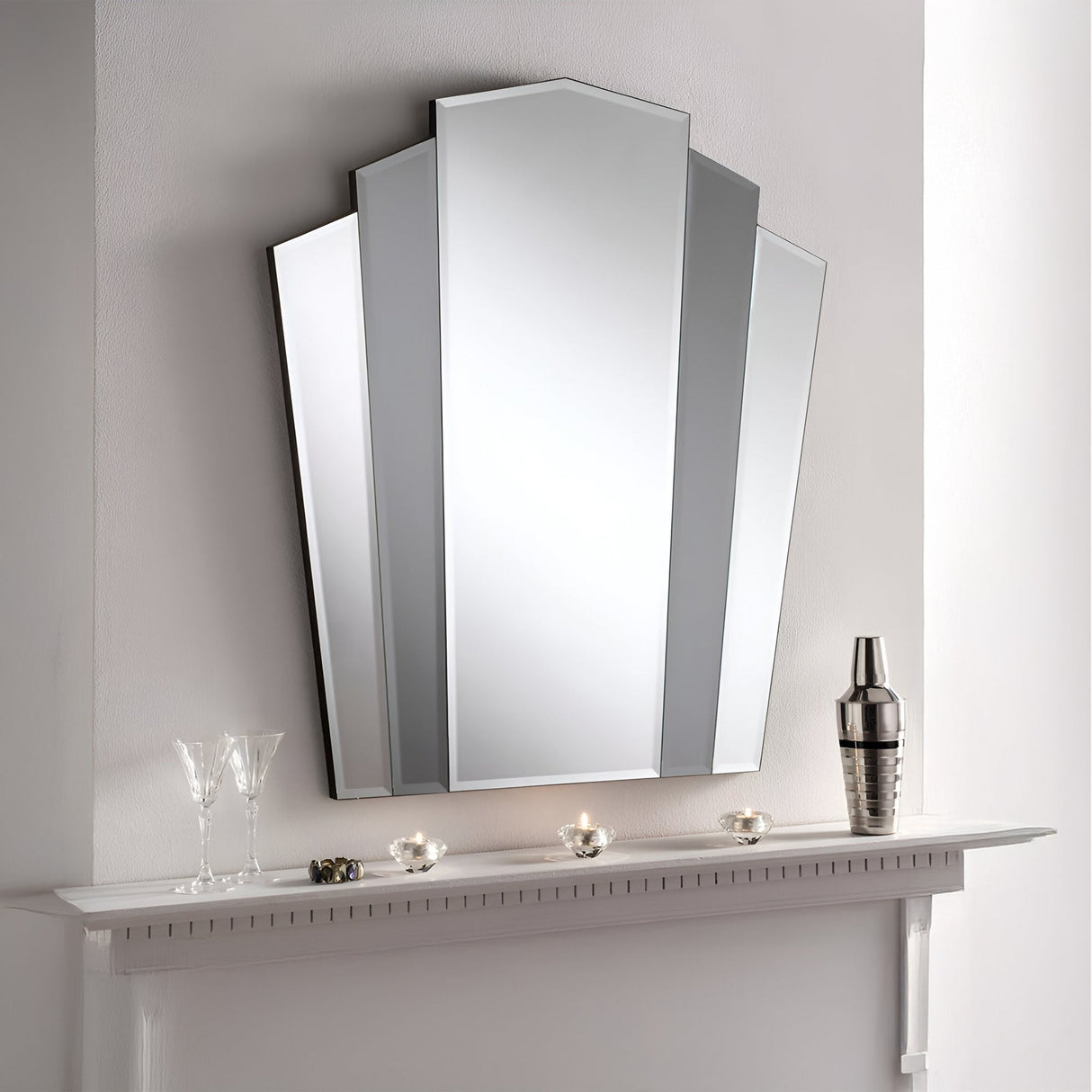 Art Deco inspiration shines in the Matisse Fan Wall Mirror Grey (90x80cm) above a white mantel. Pair with candle holders, champagne glasses, and a silver cocktail shaker for a clean, modern look against a light-colored wall.