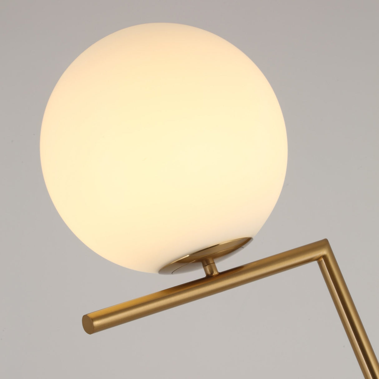 The Vetra 1 Light Opal Glass Floor Lamp features a round opal glass shade on a sleek gold stand, offering minimalist lighting and modern style against a plain, light background.