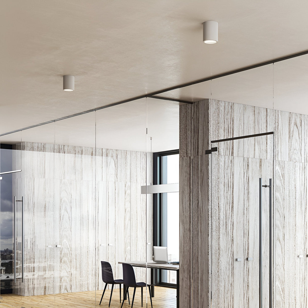 A modern office interior features wood-paneled walls and a glass partition. Inside is a minimalist desk with a laptop, a chair, and the Lucent LED Round Downlight 25W 3000K in white overhead for energy-efficient lighting. The space is bright with natural light streaming through large windows, epitomizing contemporary interiors.